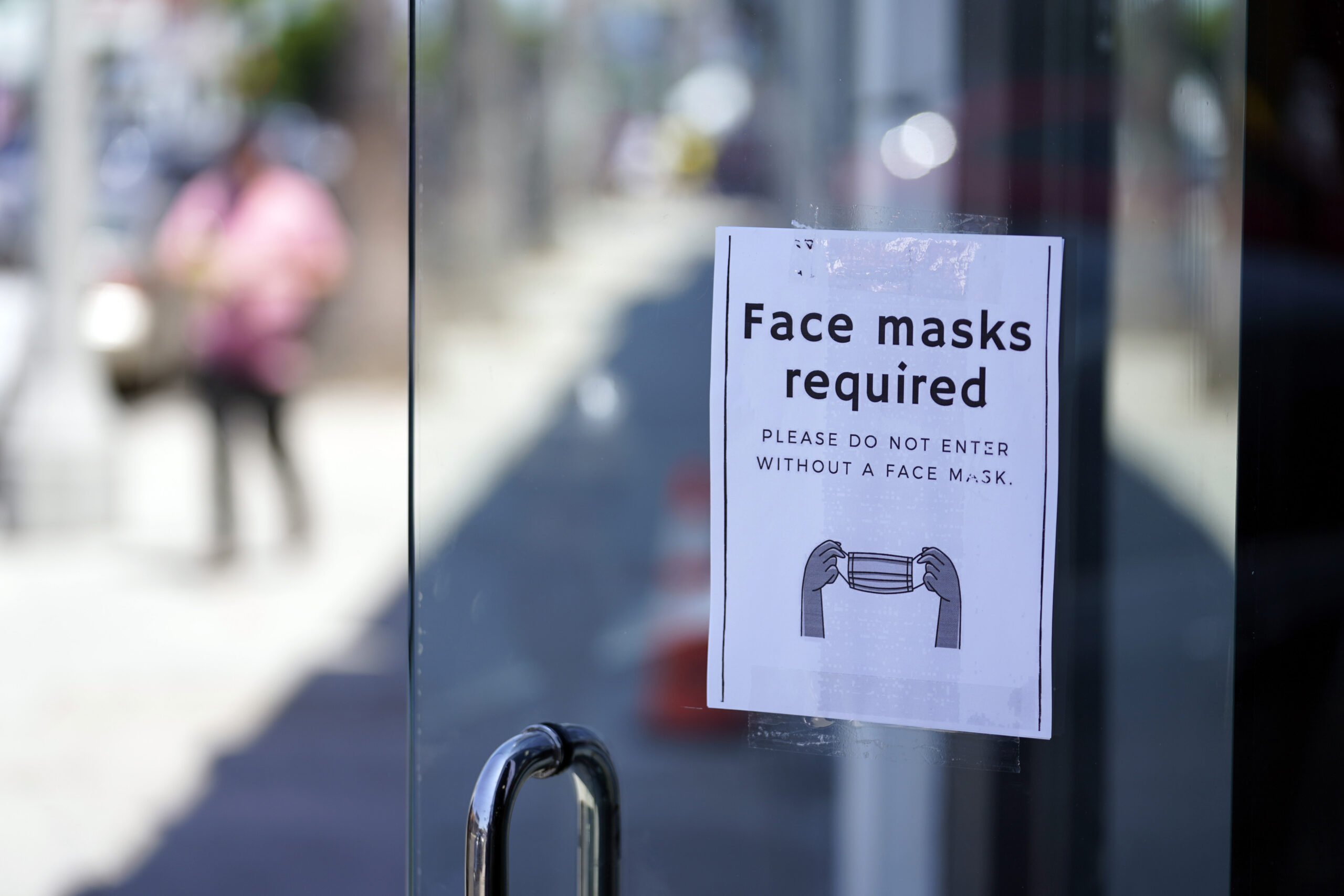A sign advises shoppers to wear masks outside of a store 