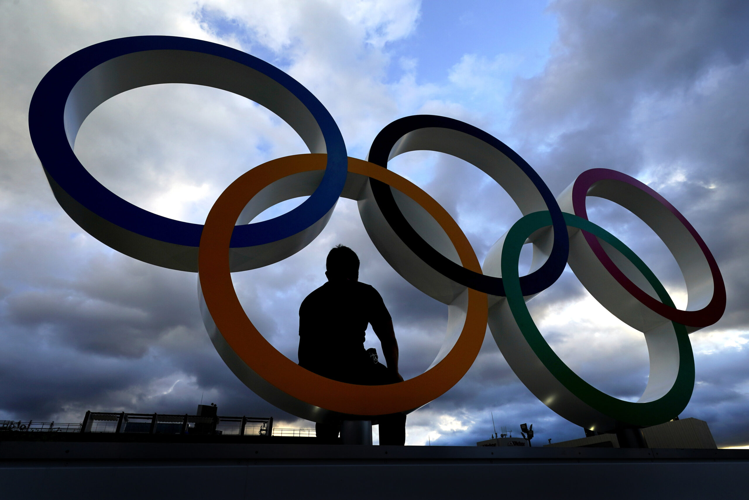 A man poses for a photo in a set of Olympic rings outside the Olympic Stadium