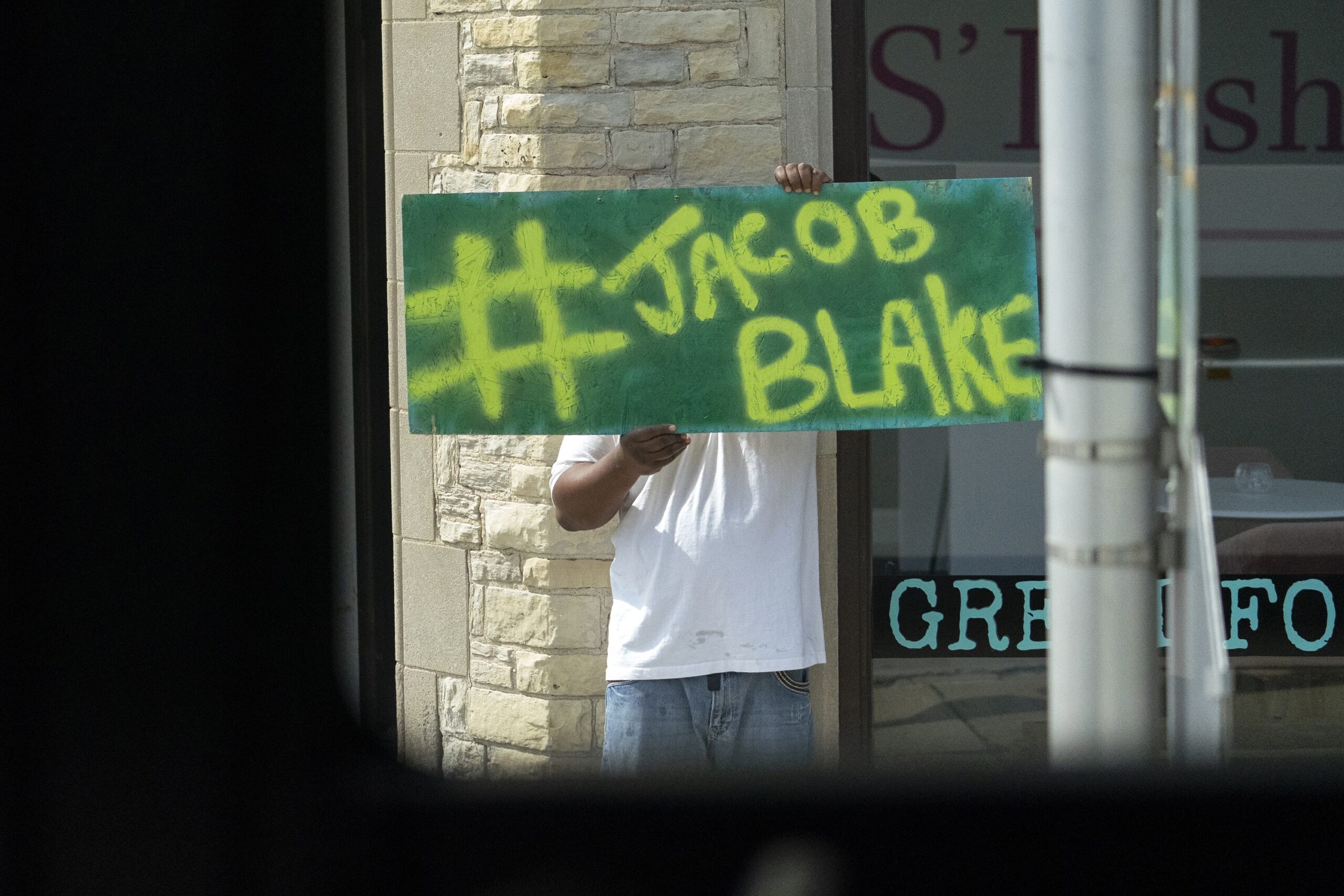 A person holds up a sign that reads "#Jacob Blake"