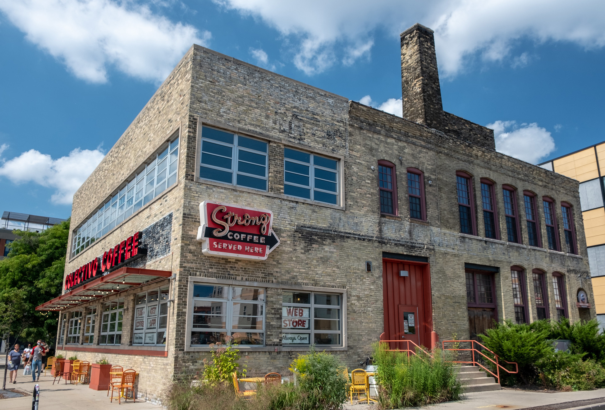 A two-story grey brick building with a red Colectivo Coffee sign