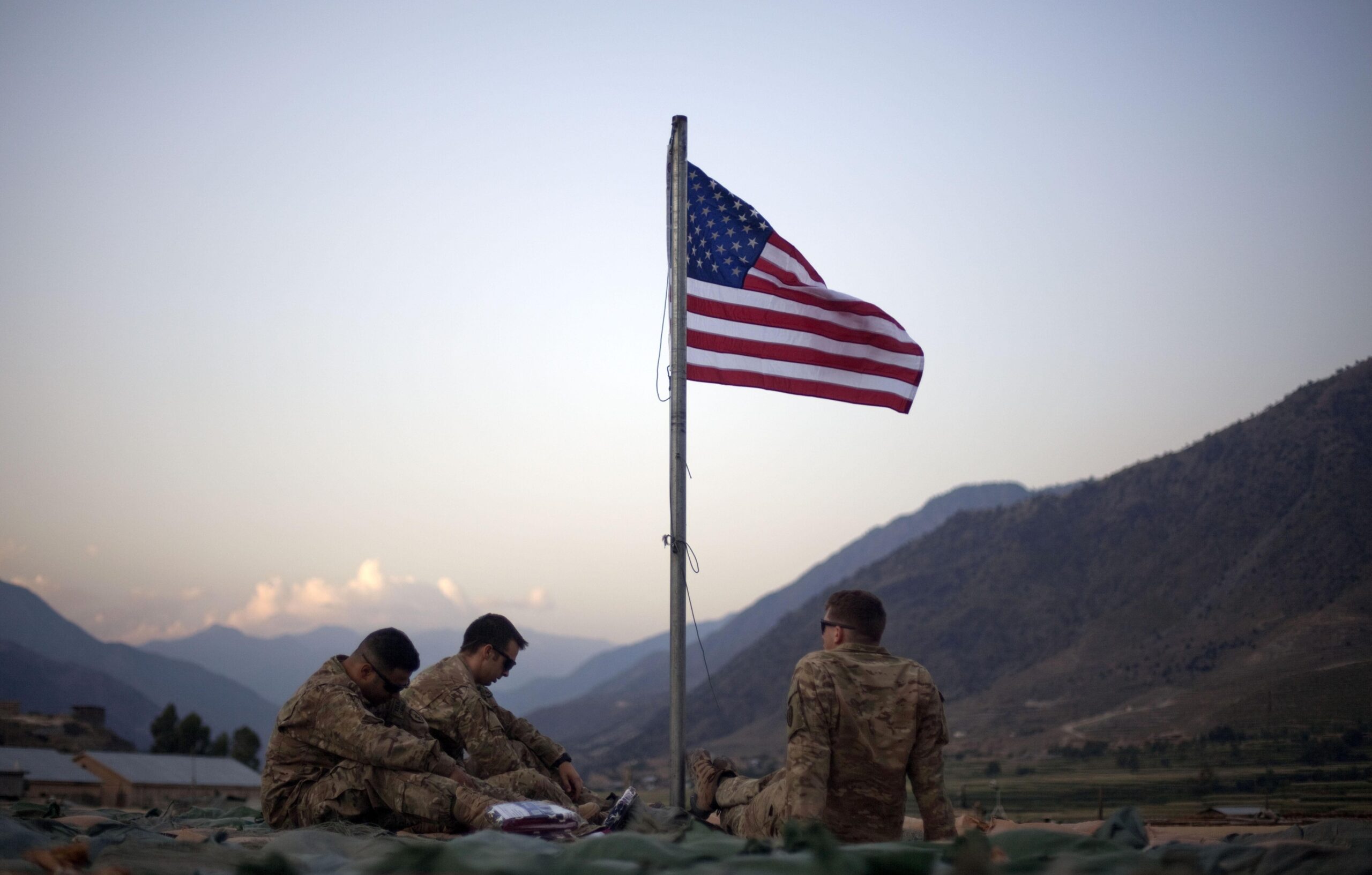 American soldier sit beneath an American flag in Kunar province, Afghanistan