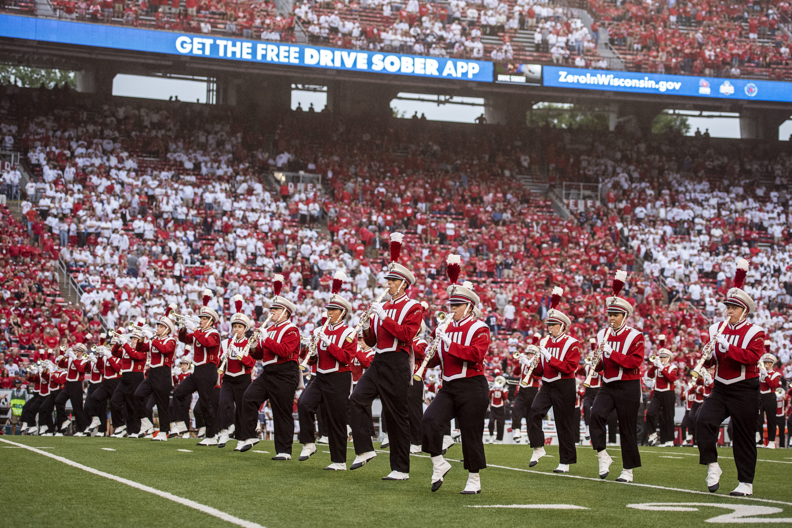 Members of the marching band perform in front of a crowded stadium.
