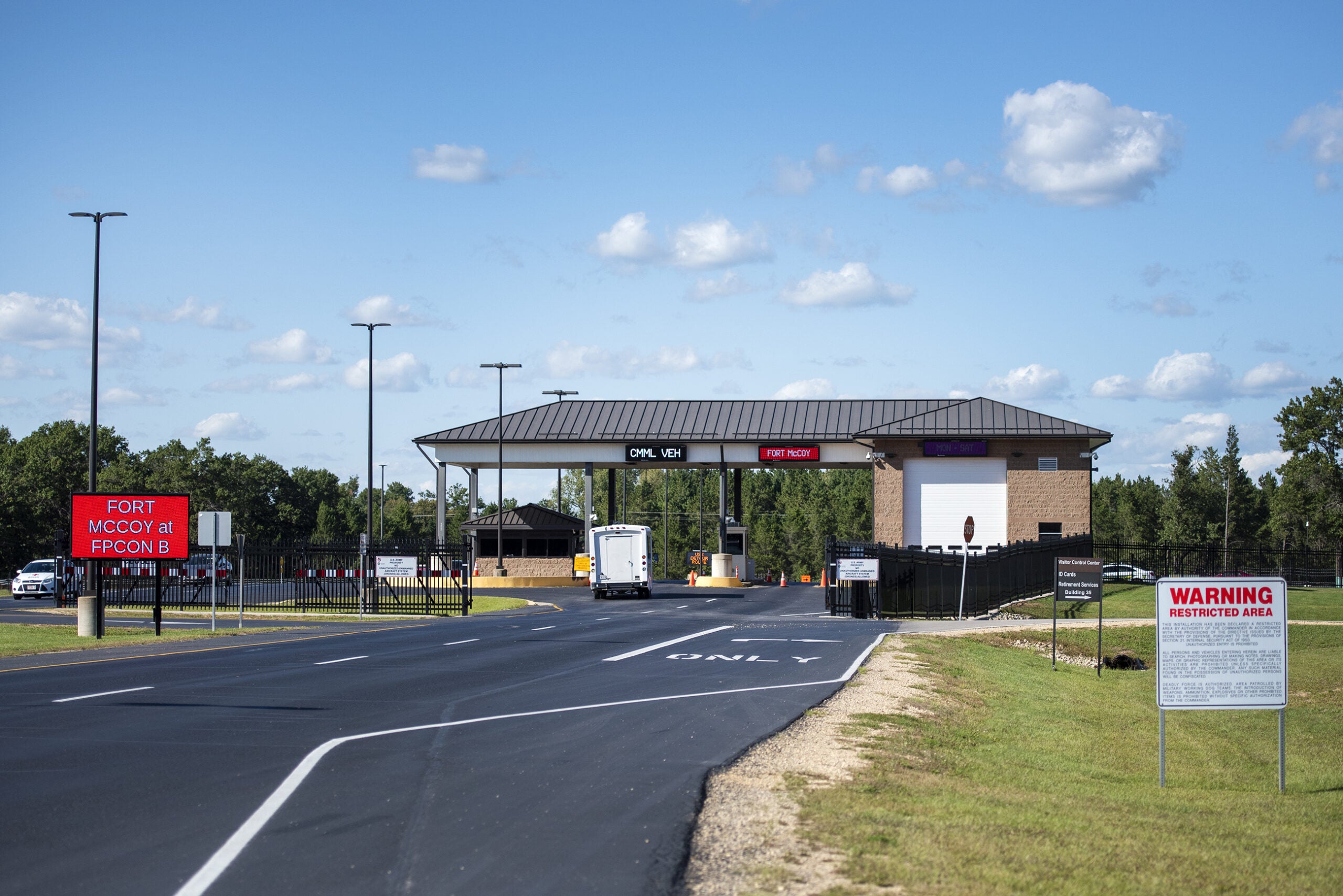 A road leads to a security check point building and into Fort McCoy.