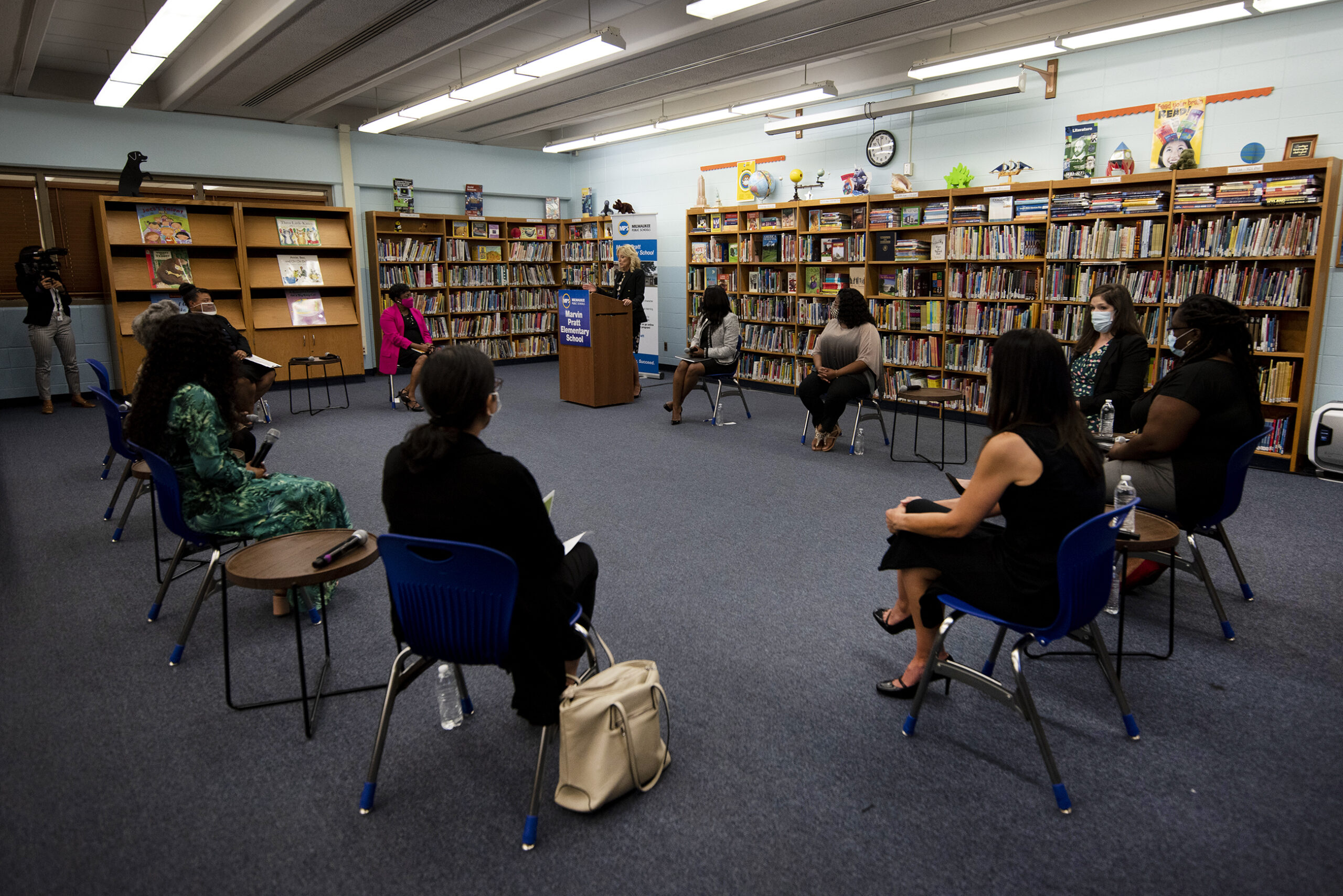 People sit facing each other in chairs inside of a school library.