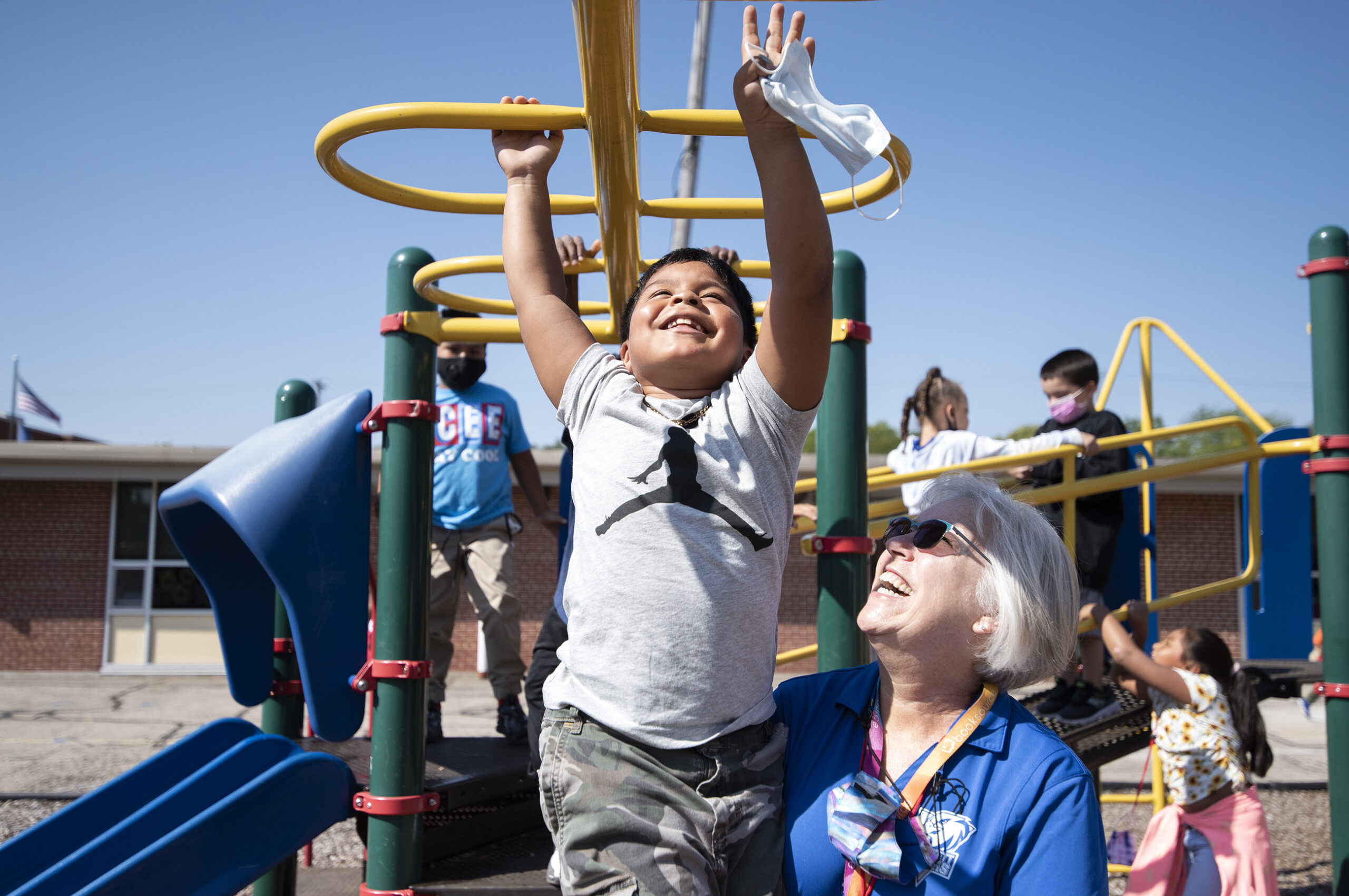 A student smiles as he reaches for the next monkey bar while playing outside on the playground.
