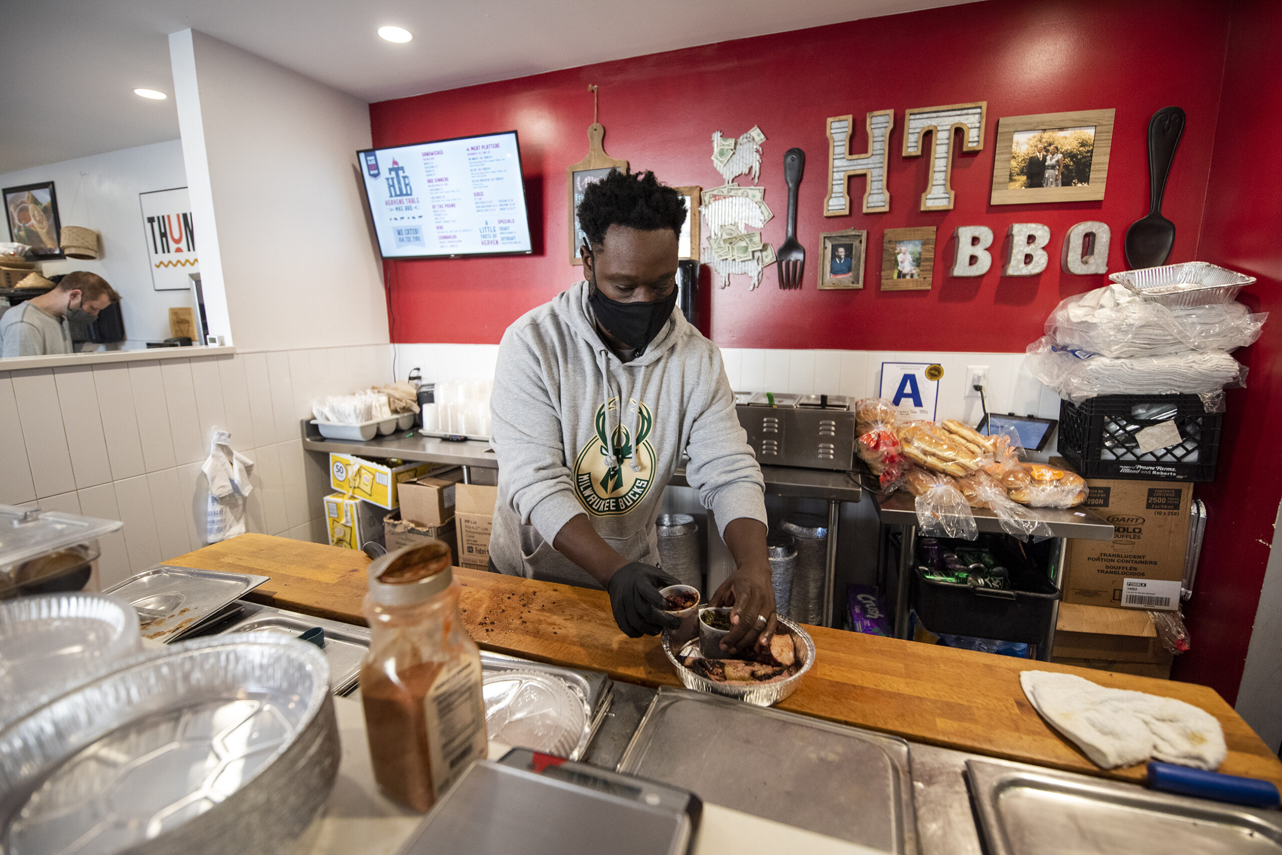 A man places containers of food into a to-go box behind a counter.