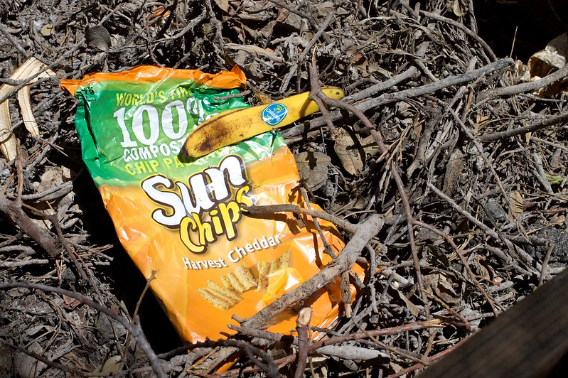 A sun chips bag is a bright spot of color in a compost pile.