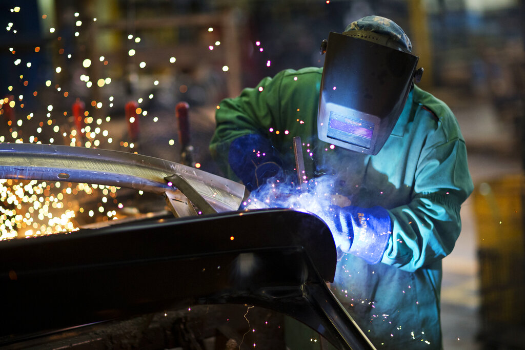 Sparks fly as a welder works on a frame for a school bus