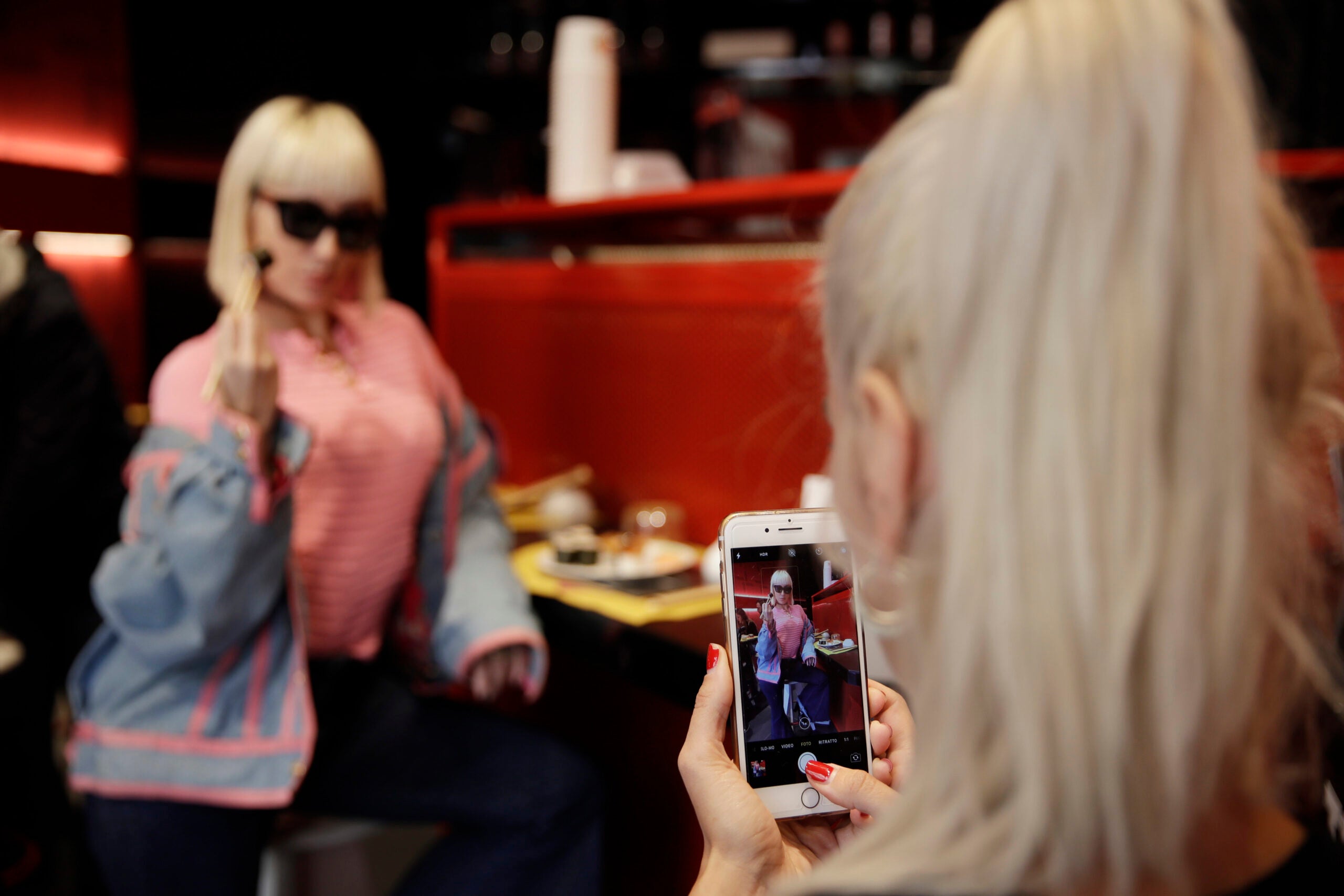 Person photographs another person at restaurant
