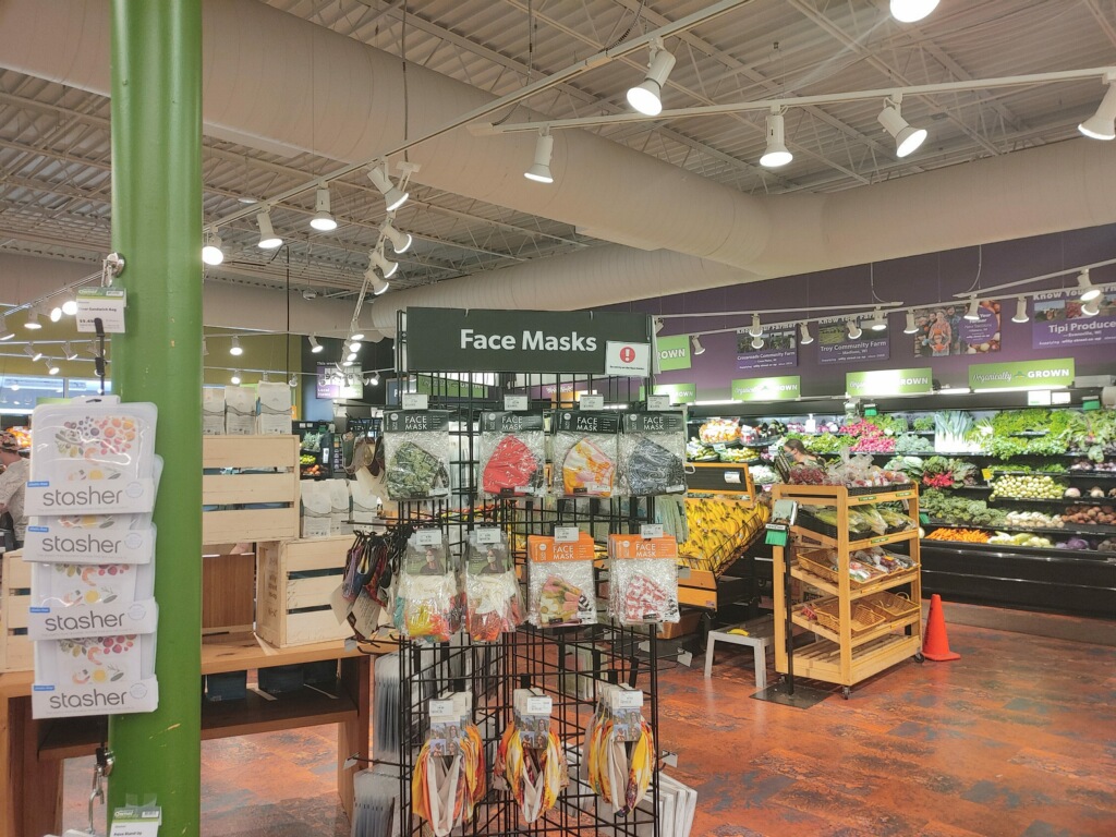 A grocery store produce section that includes a face mask rack