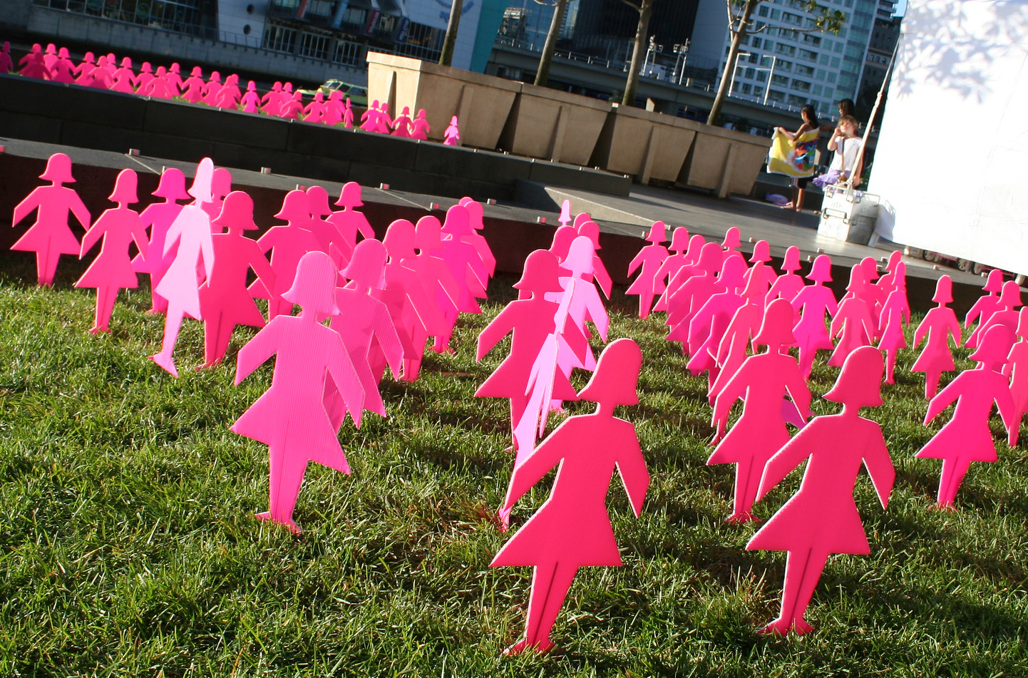 Pink woman cut outs on lawn.