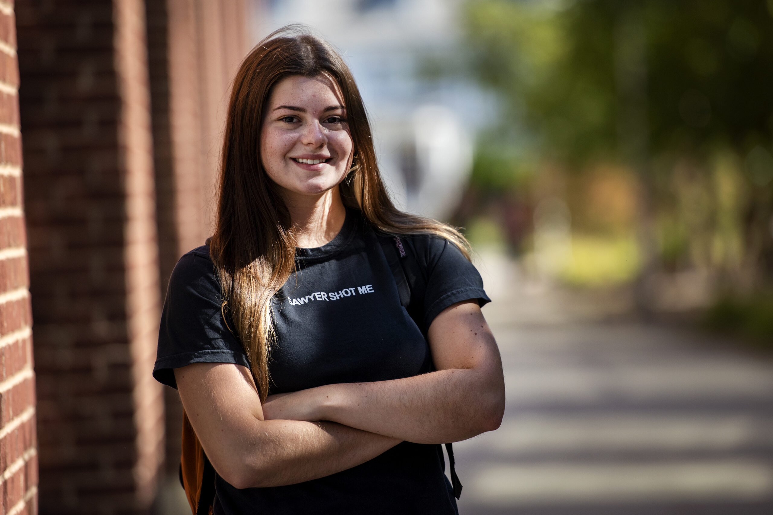 A student stands with her arms crossed on campus.