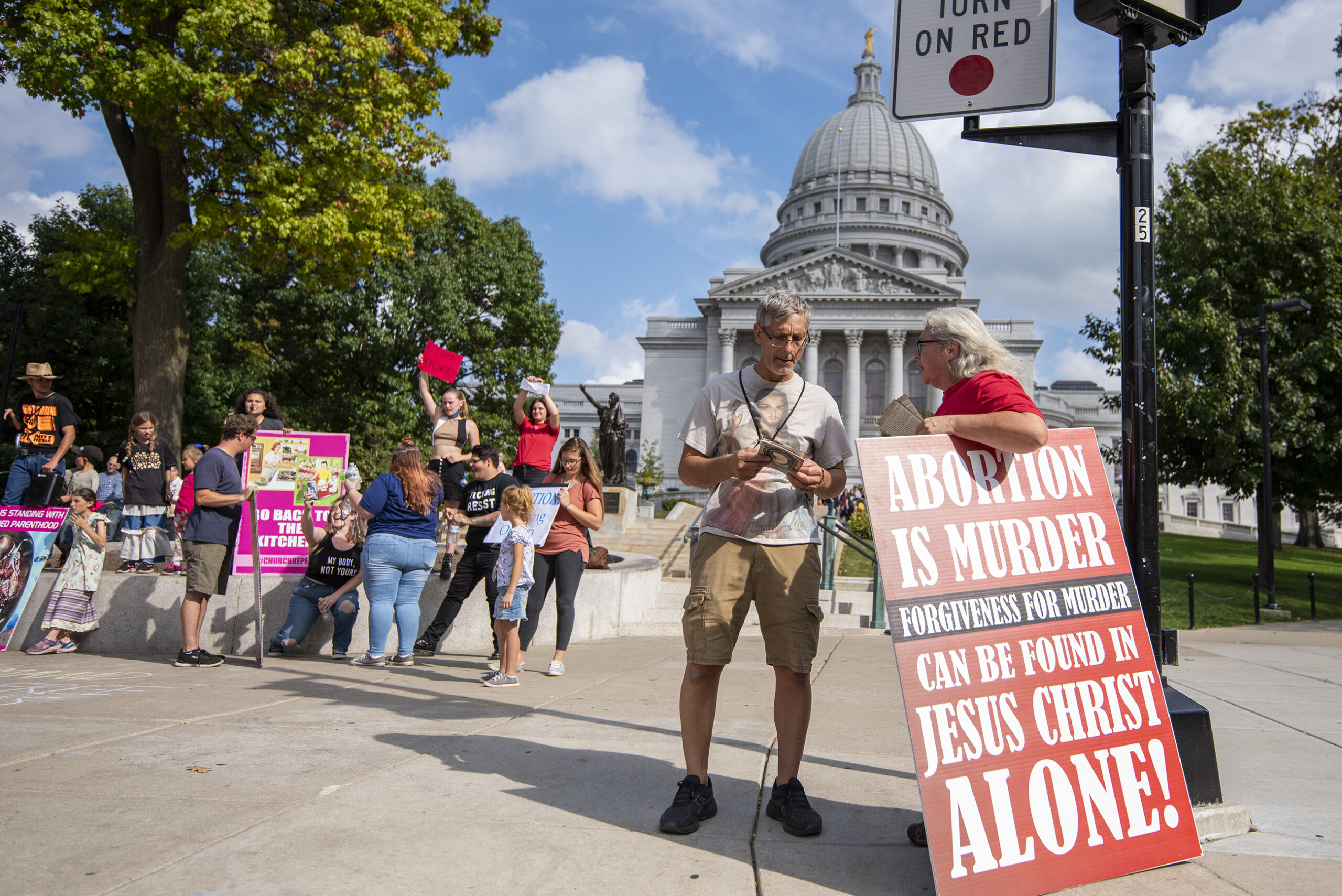 A pro-life protester holds a red sign in front of the state capitol.