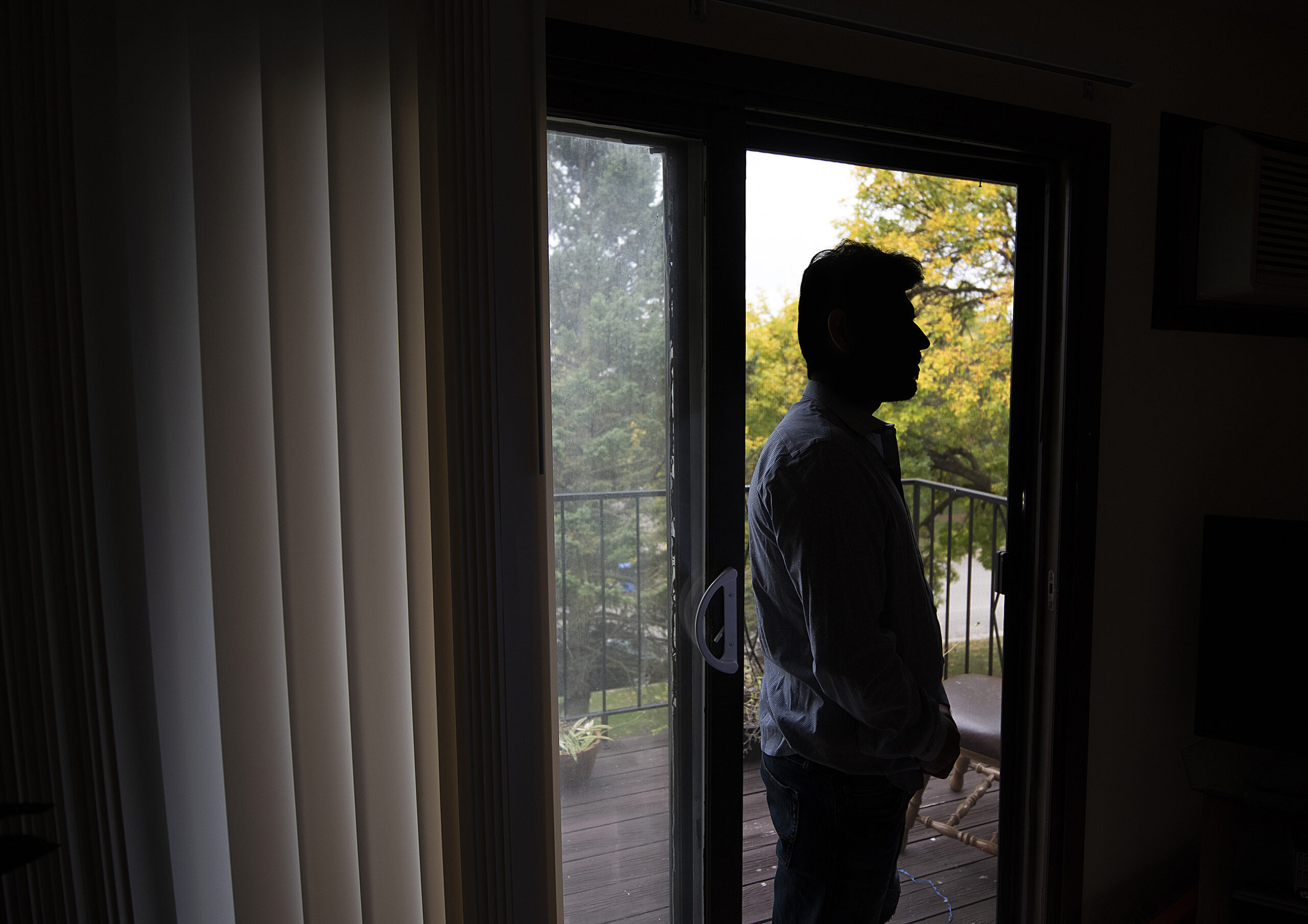 Johnny is seen in silhouette in front of a window in his apartment.