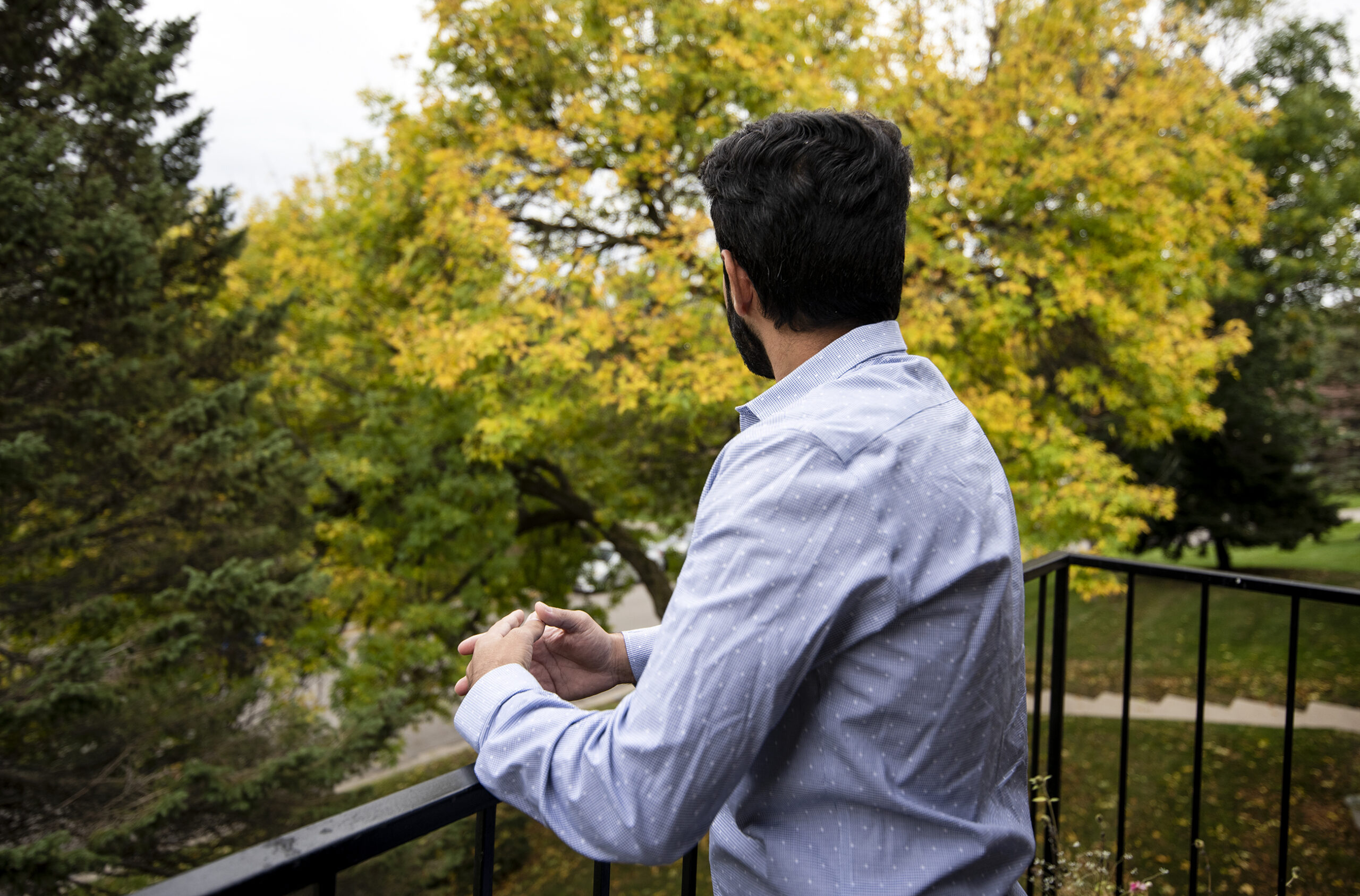 Johnny looks out into a fall landscape from an outdoor balcony.
