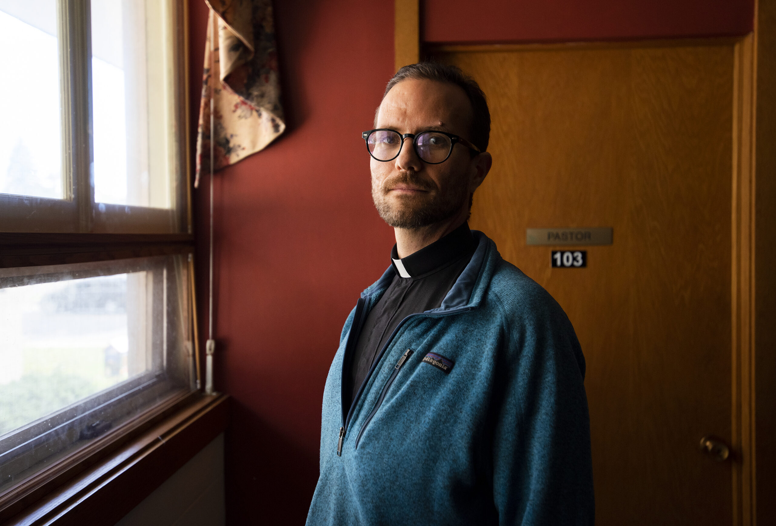 The Rev. Jonathan Barker is illuminated by window light.