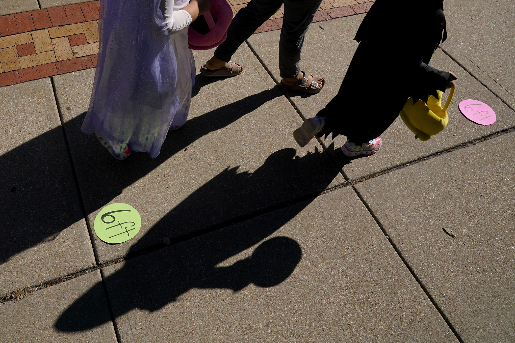 People walk past social distancing markers as they trick-or-treat for Halloween