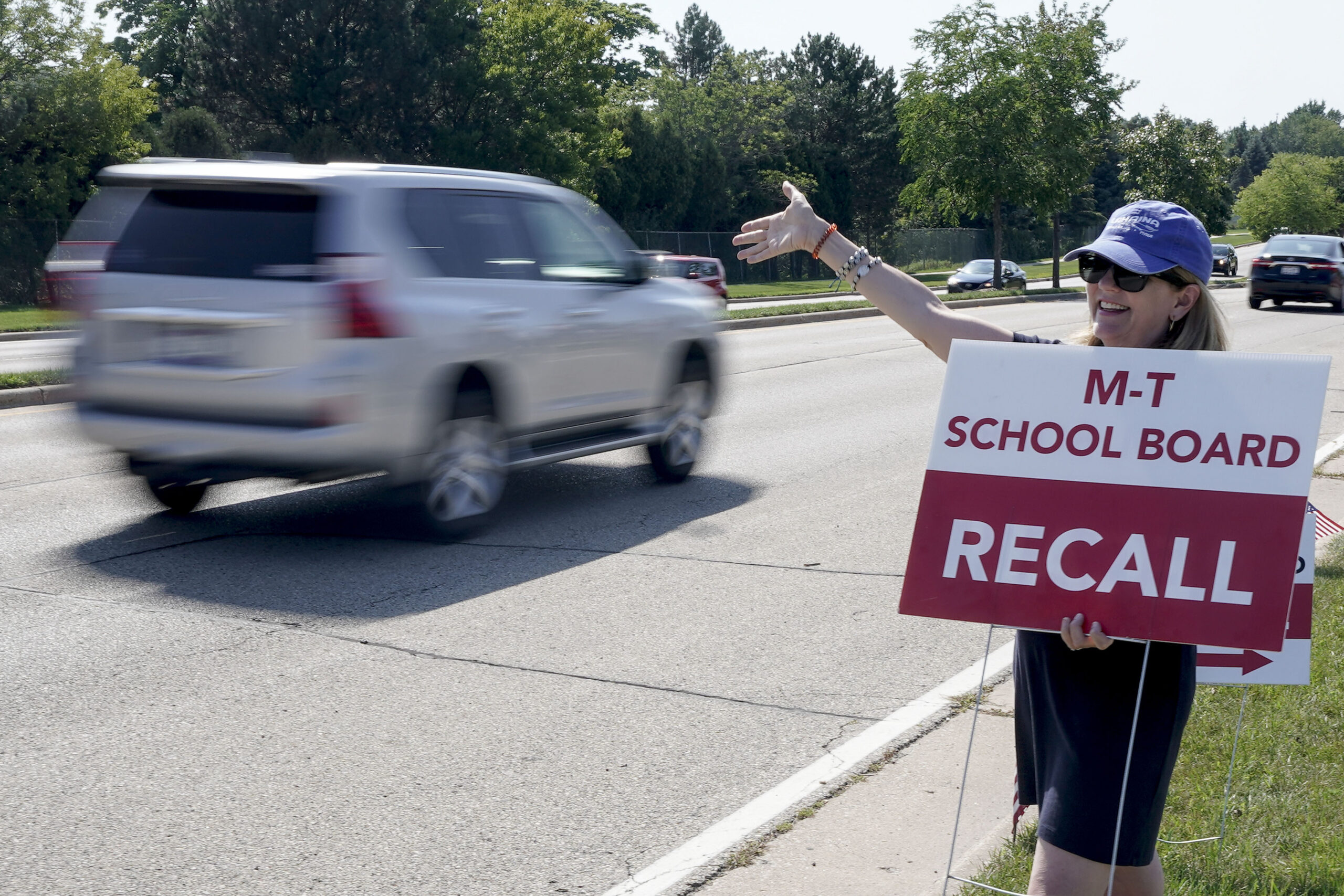 Maureen Hall, a supporter of recalling the entire Mequon-Thiensville School District School Board, waves at drivers