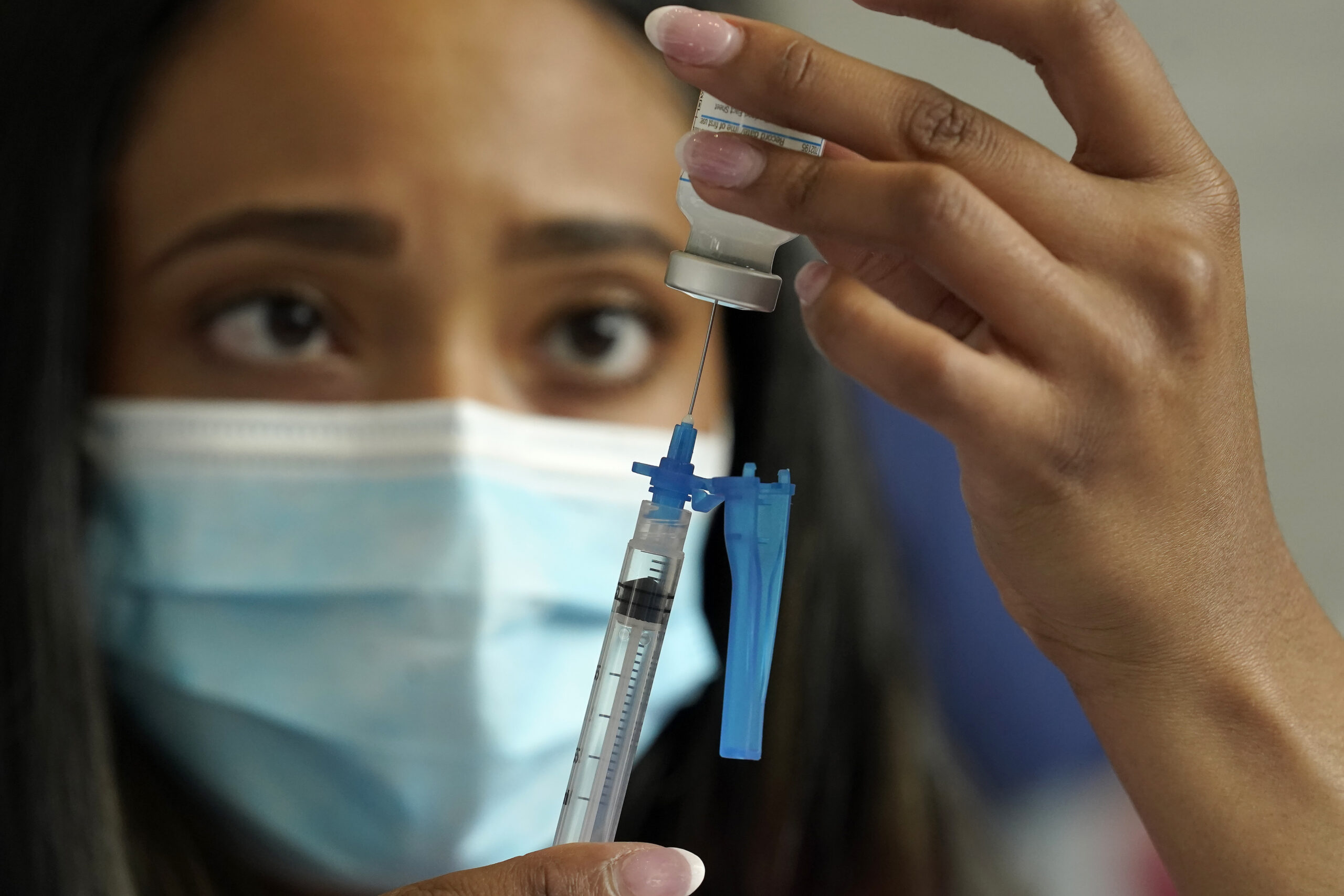 A nurse draws a Moderna COVID-19 vaccine into a syringe