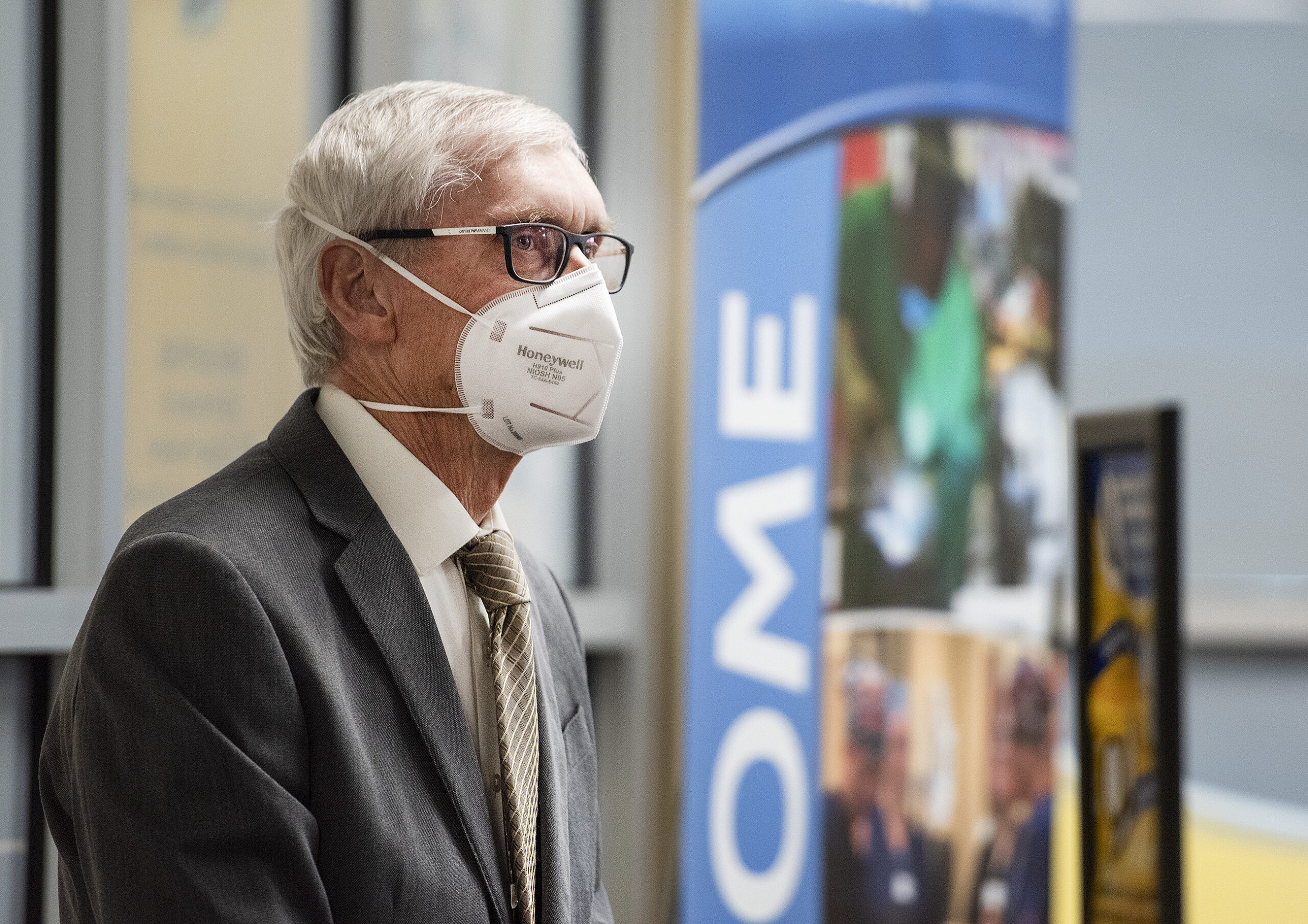 Gov. Tony Evers wears a face mask as he looks at the reporters at the press conference