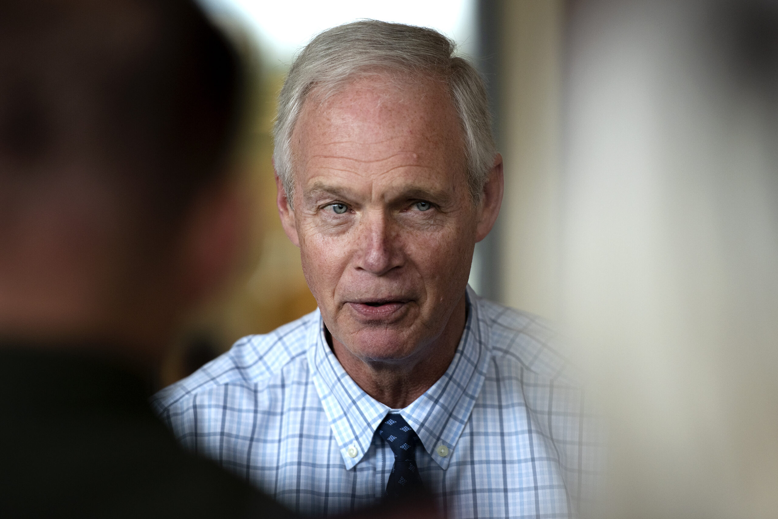 Sen. Ron Johnson is seen between people crowded to listen to him answer questions.
