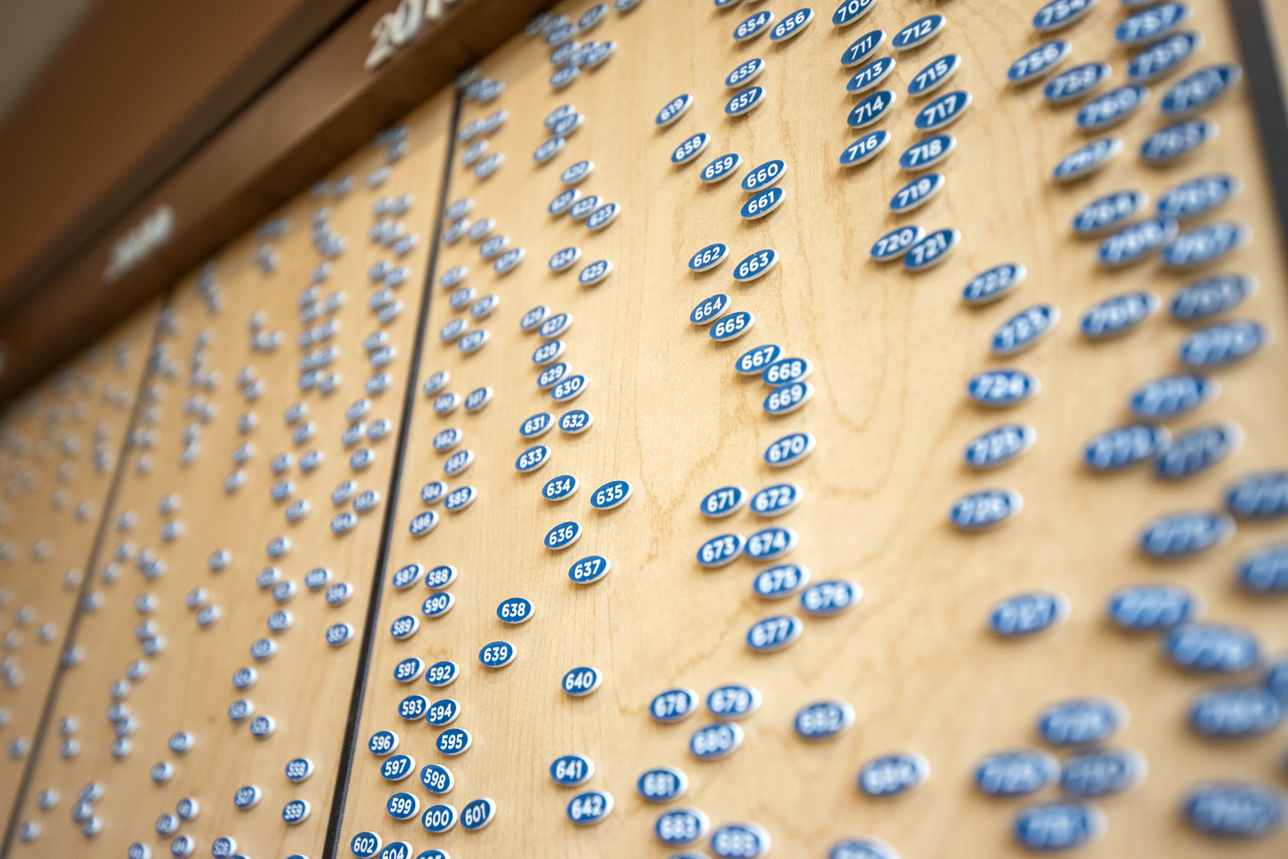 A large quantity of blue ovals with white numbers are stuck onto a wooden board inside the headquarters.
