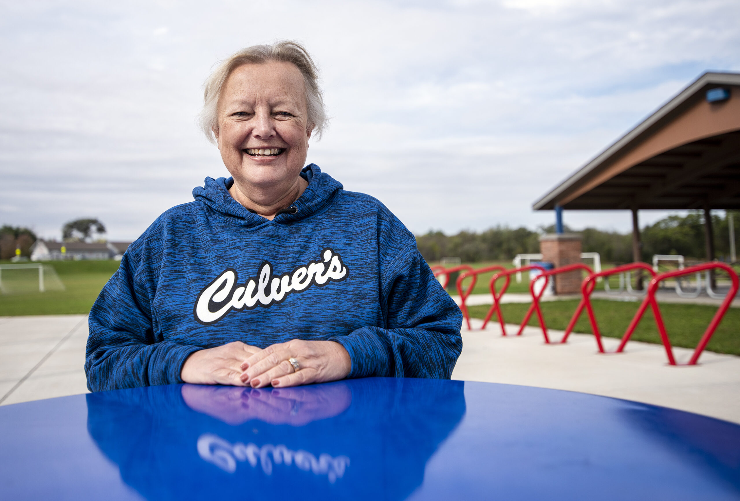 Rita Larsen wears a blue Culer's hoodie as she sits outside at a park.