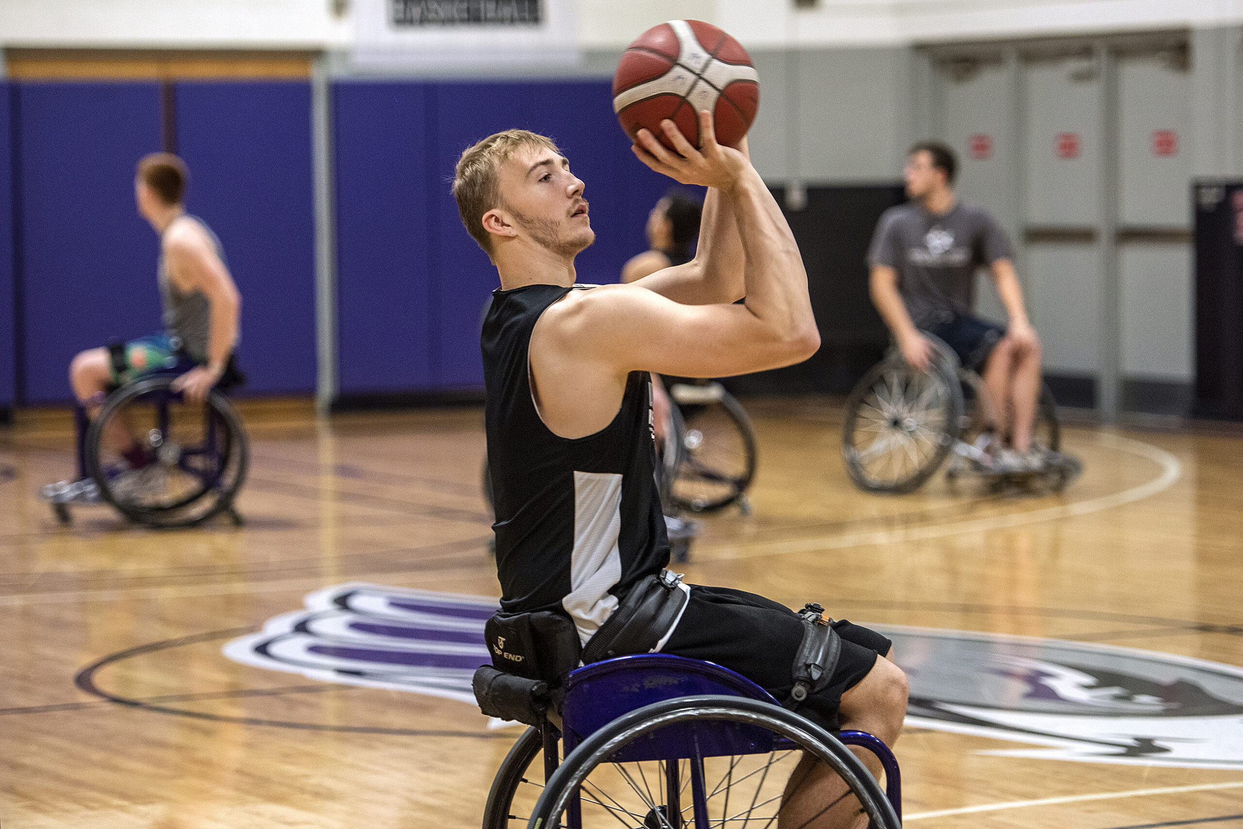 A player in a wheelchair holds the basketball and gets ready to shoot.
