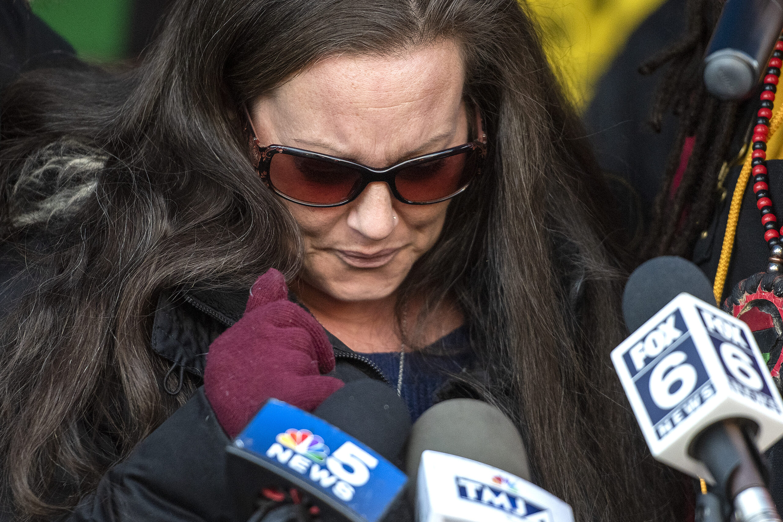 A woman looks down to gather her thoughts before speaking to reporters.