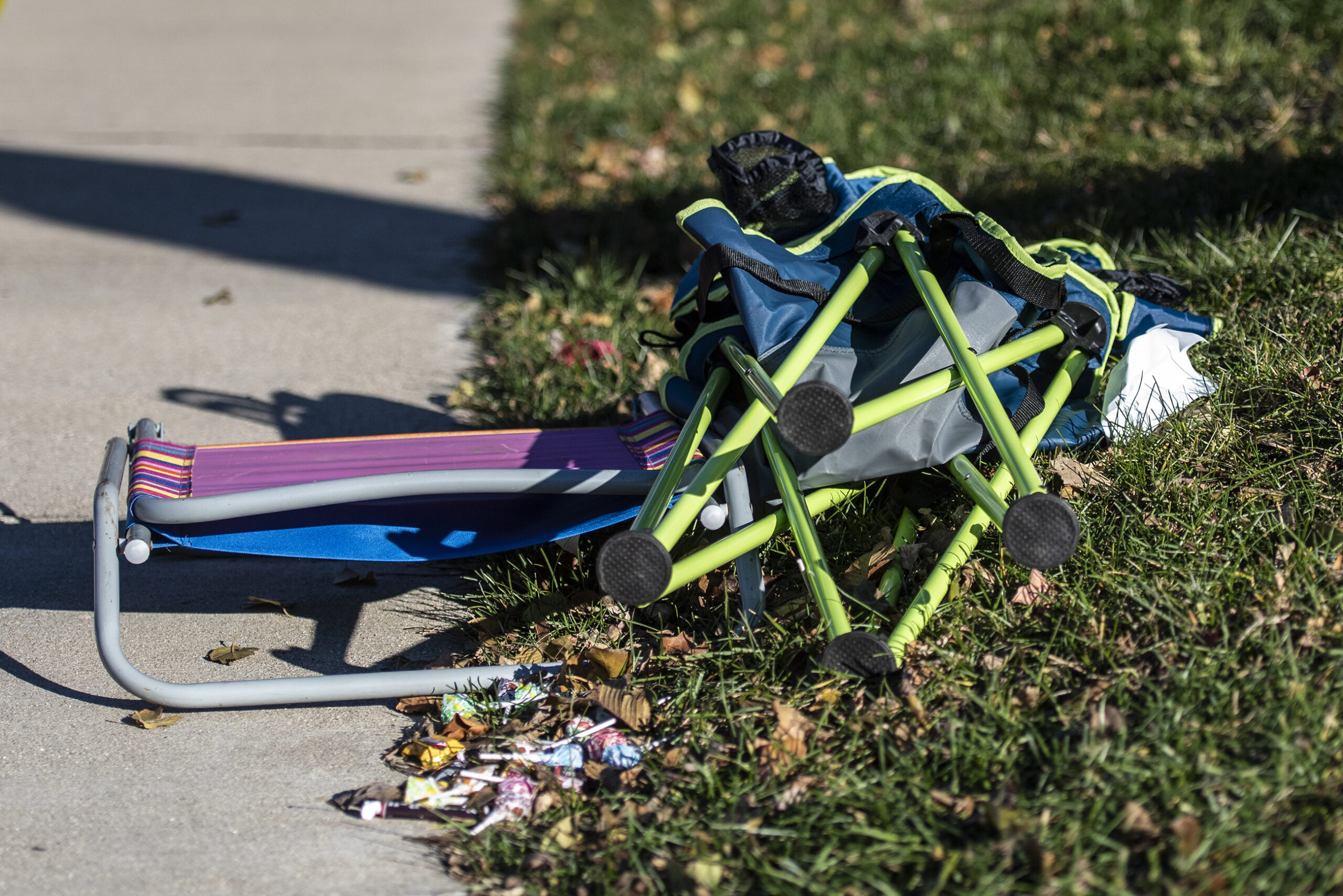 A folding chair and candy are left on the side of the sidewalk.