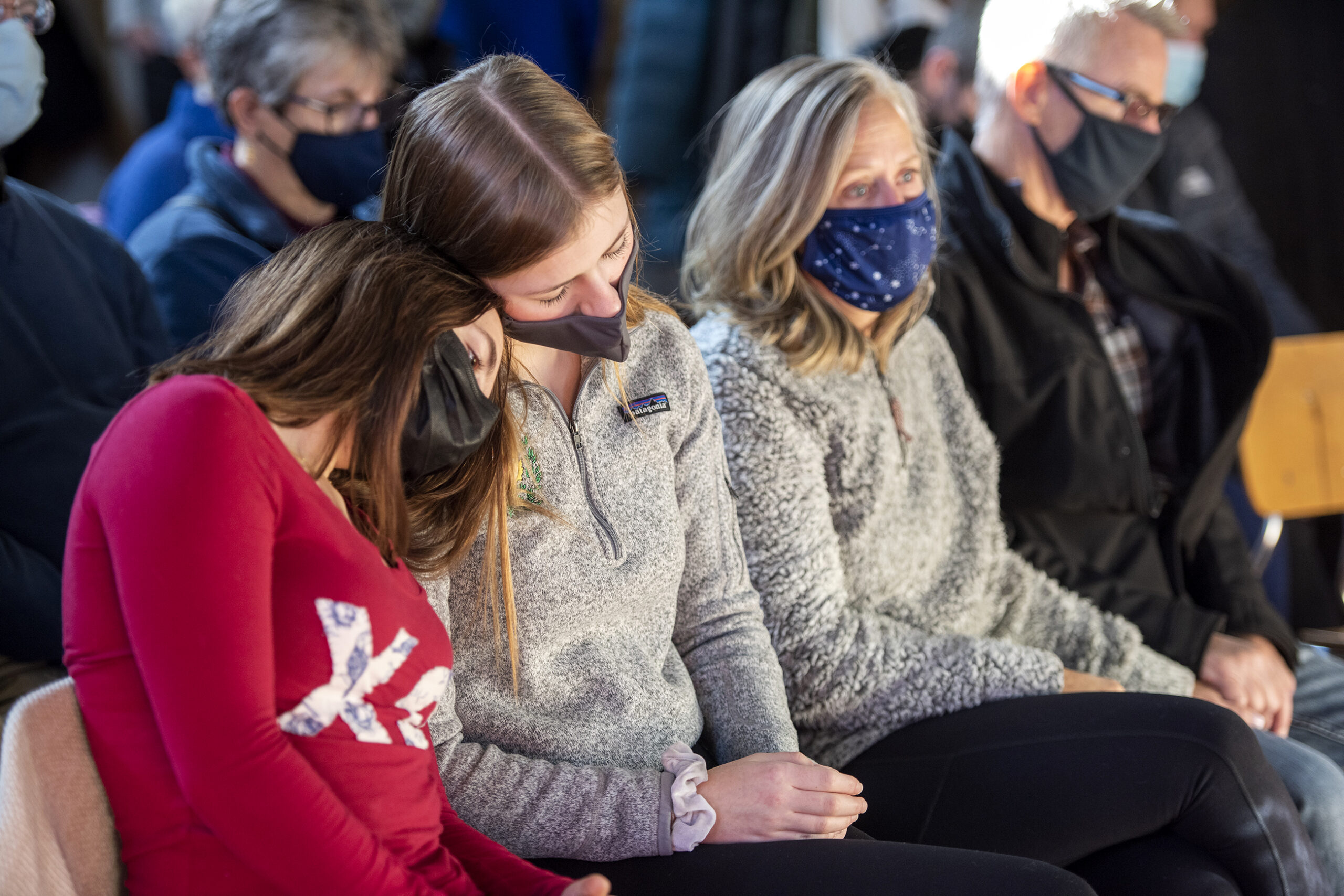 Two students lean their heads together as they pray with other attendees.