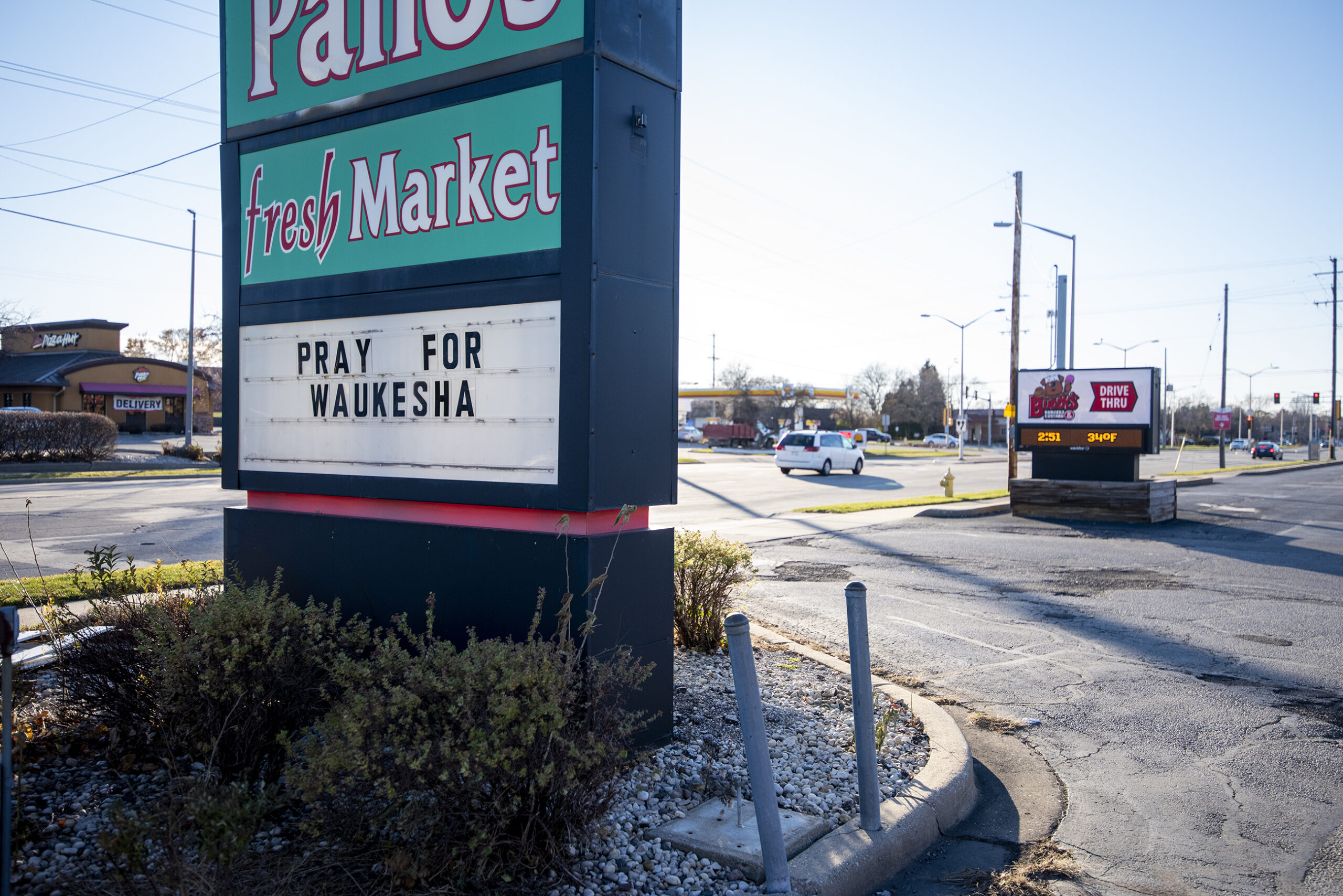 A business' sign says "Pray for Waukesha" as cars drive by.