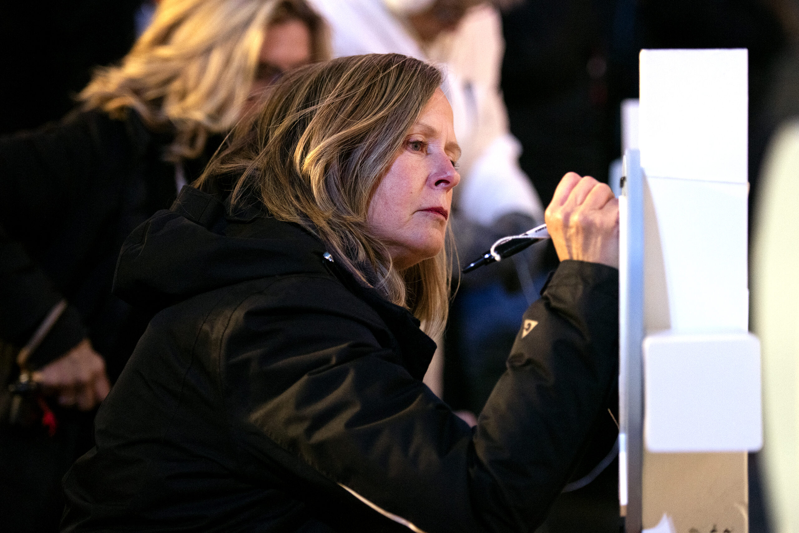 A woman writes on a white cross.