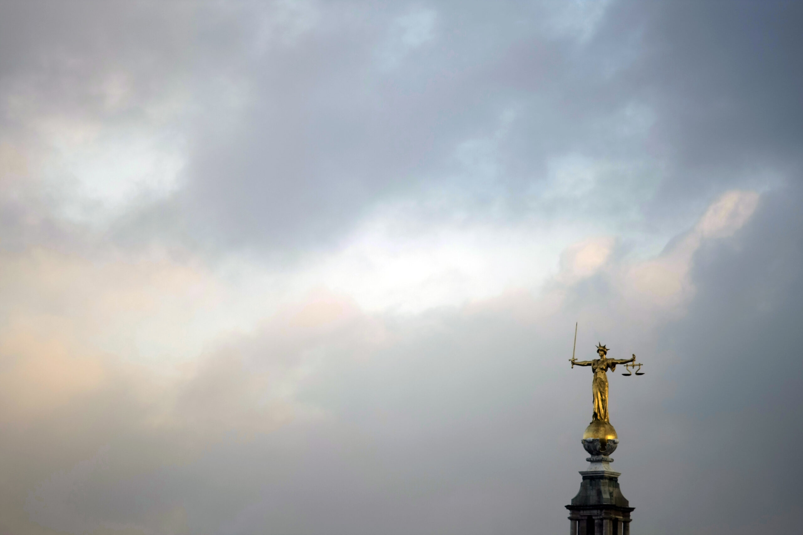 Lady Justice statue in front of clouds