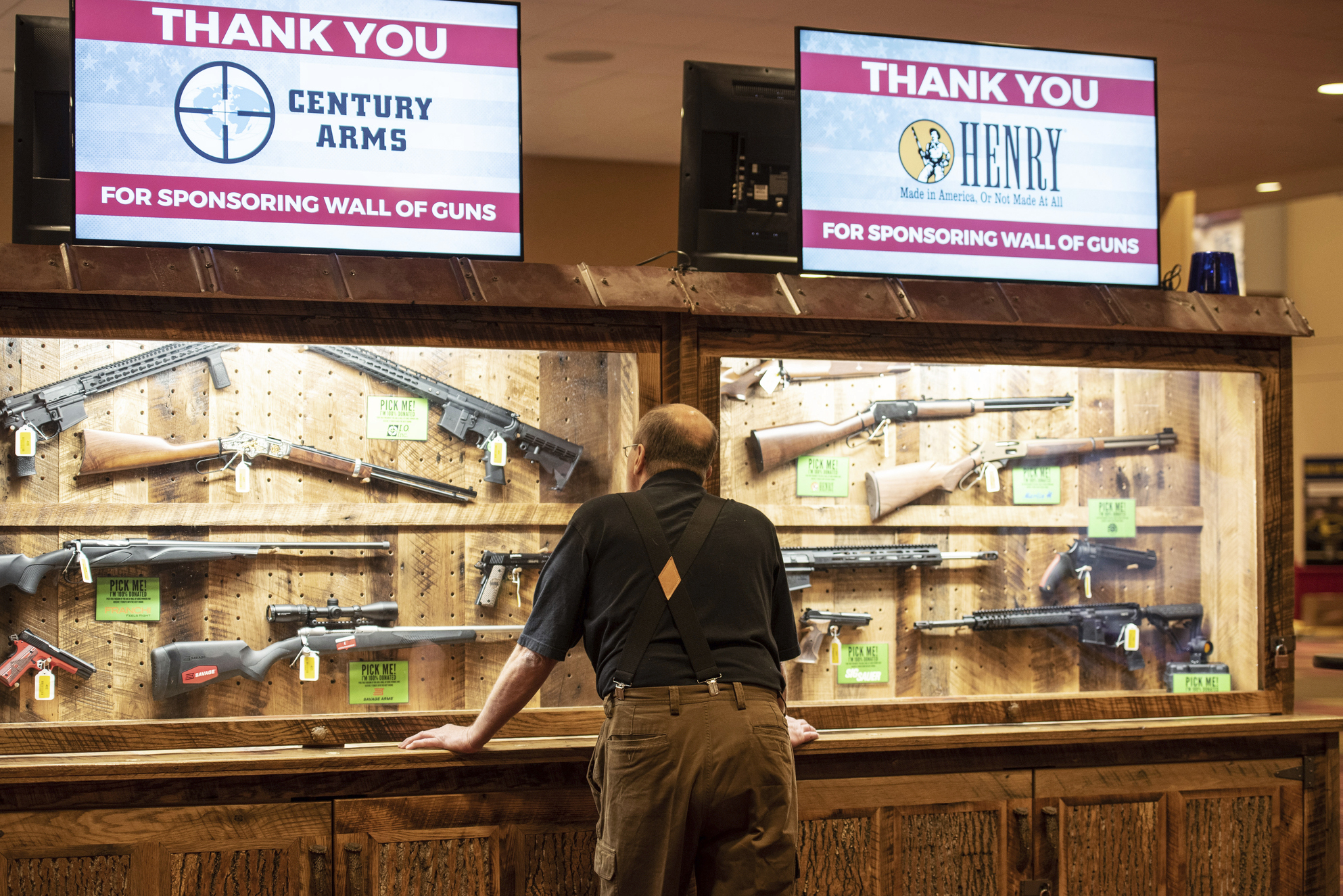 A man looks at a display case of firearms