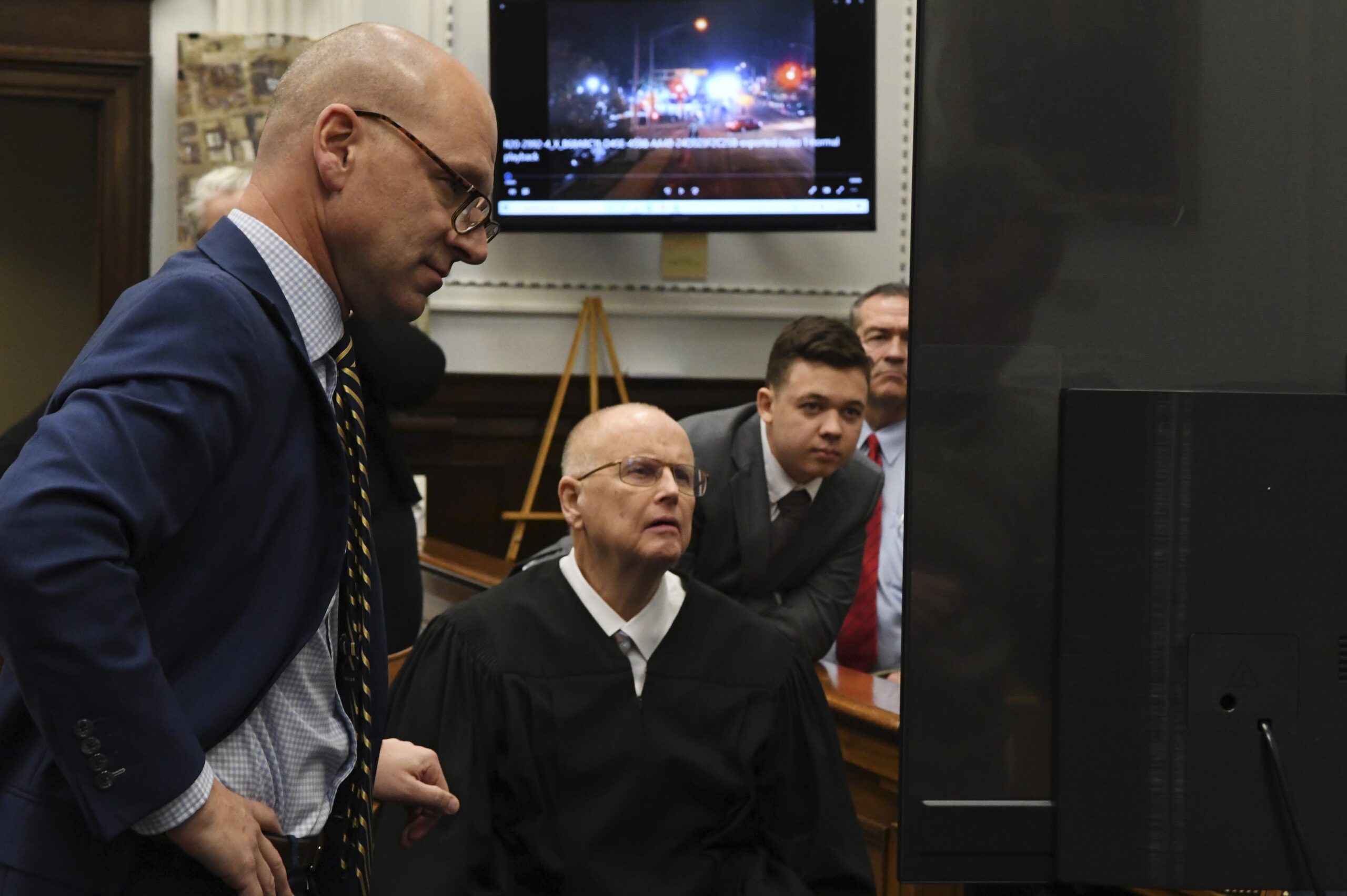 Defense attorney Corey Chirafisi, Judge Bruce Schroeder and Kyle Rittenhouse look at video screen