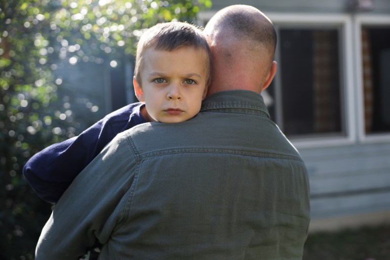 A 4-year-old boy is held by his father