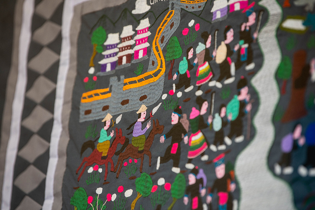 Hmong story cloth depicts people walking near river
