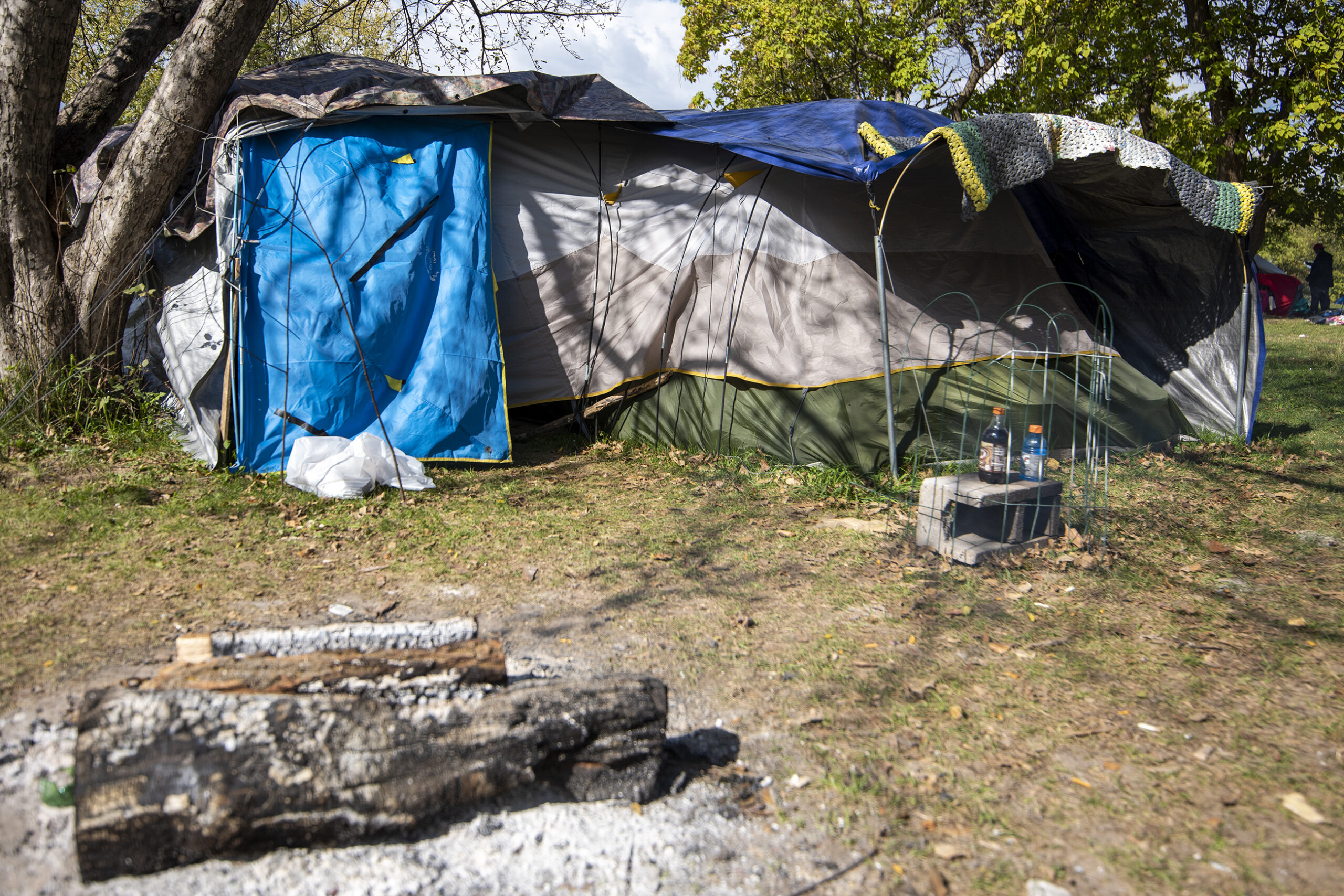 Tarps cover a tent where firewood is set up outside.