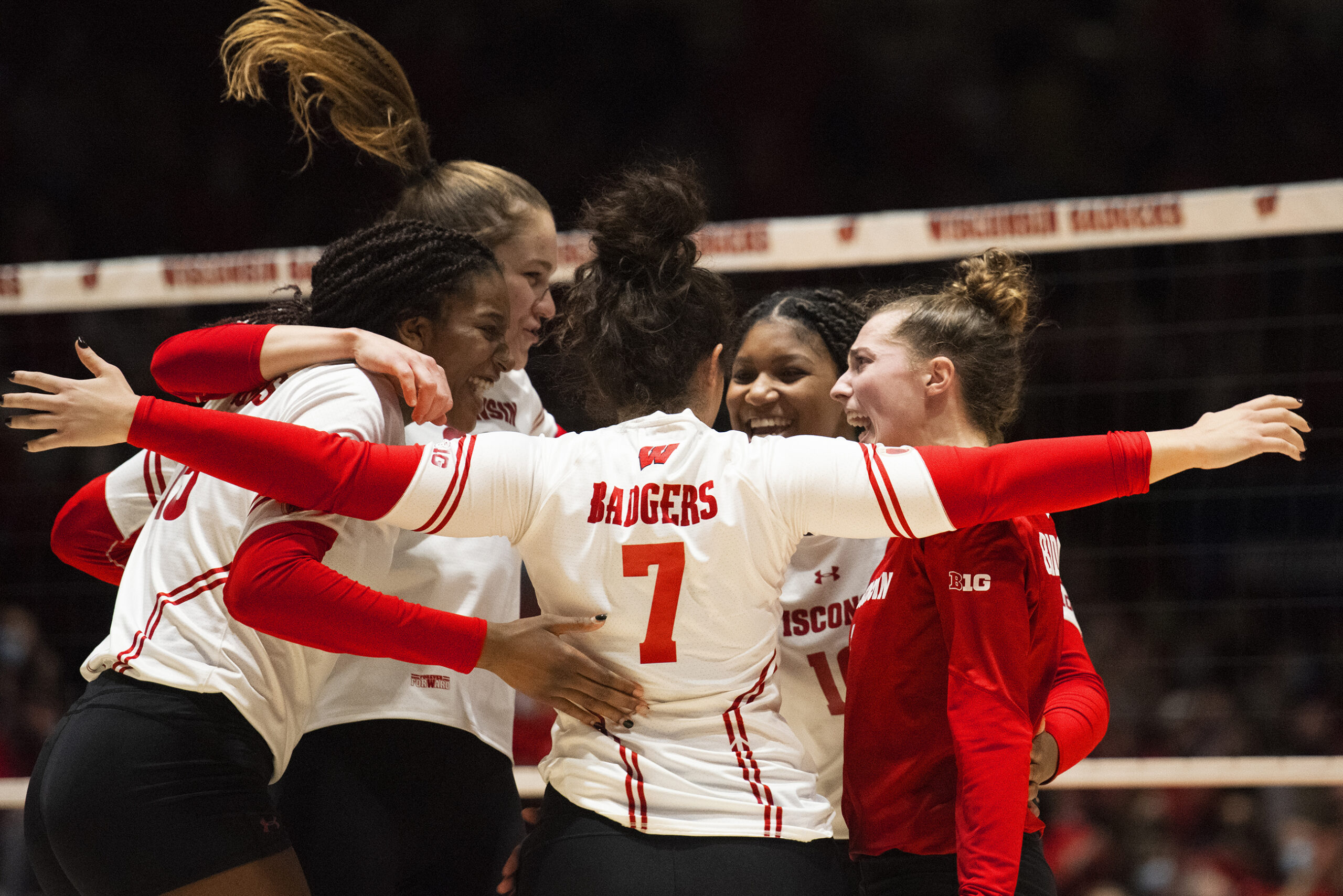 Members of the team smile as they huddle up on the court.