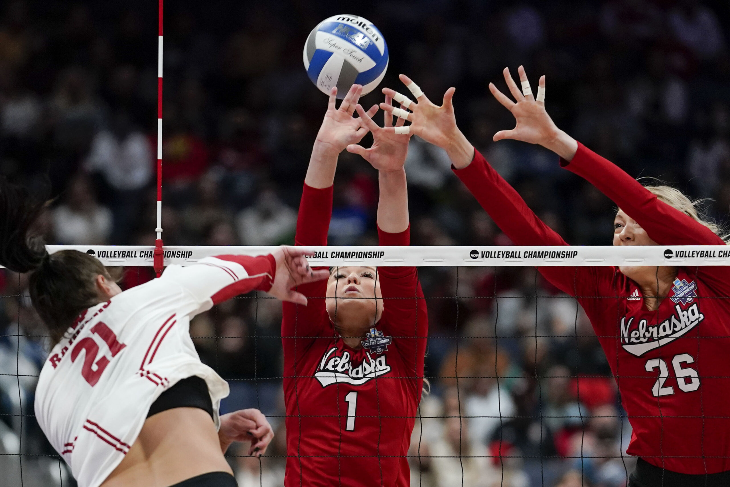 Wisconsin volleyball player Grace Loberg hits a ball against two blockers from Nebrasks
