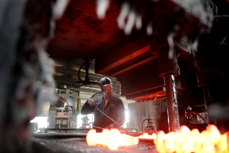 A man works at a forging press