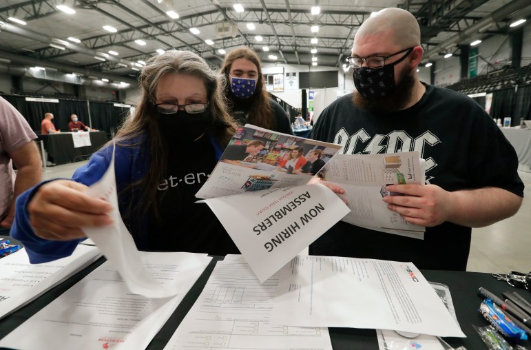 People go through documents at a table at a job fair