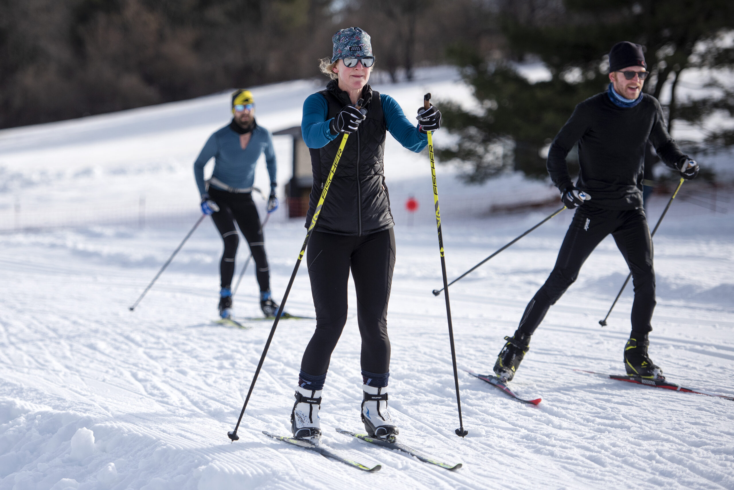 Three people hold poles as they ski