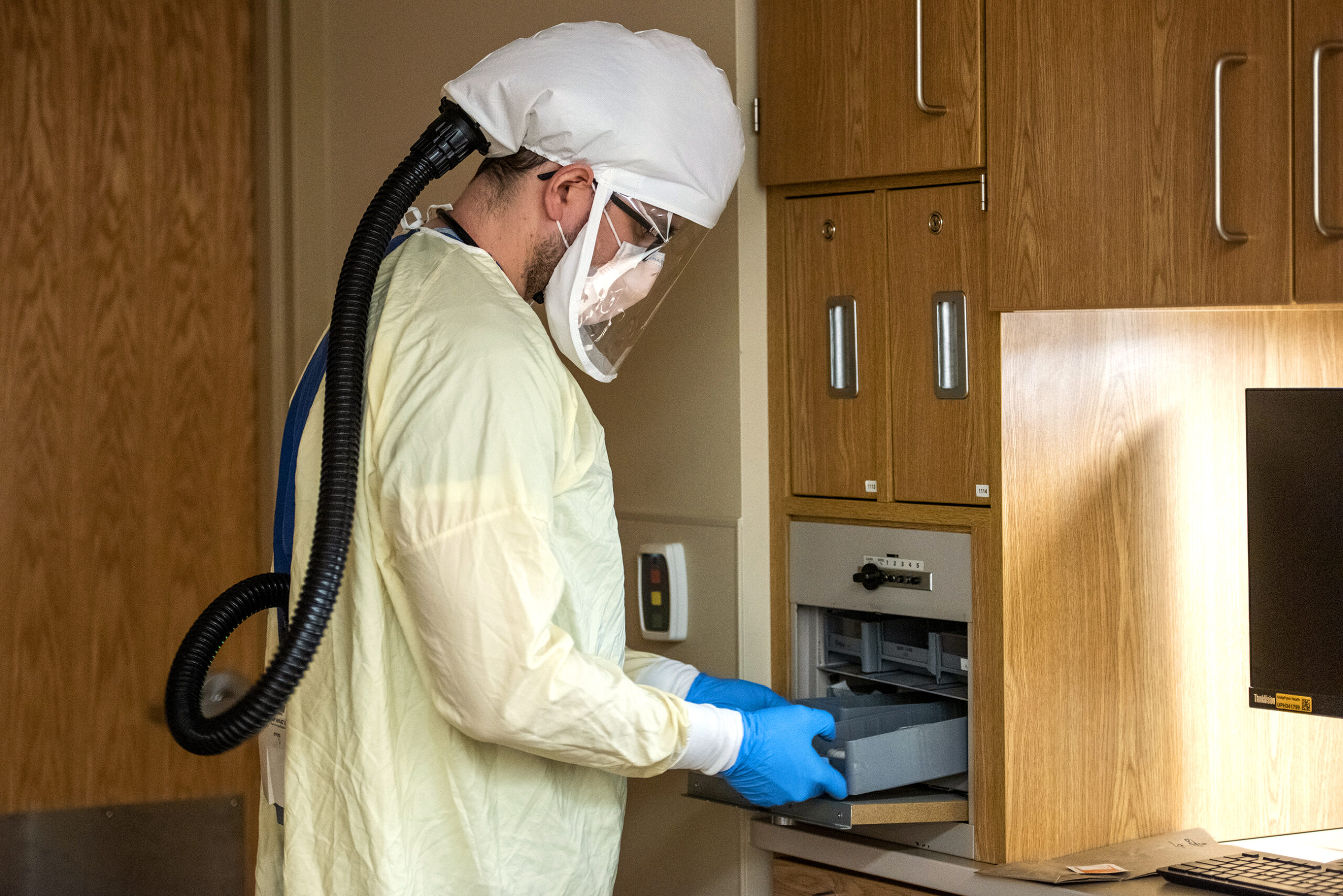 A nurse in protective gear covering his face gets ready to enter a hospital room.