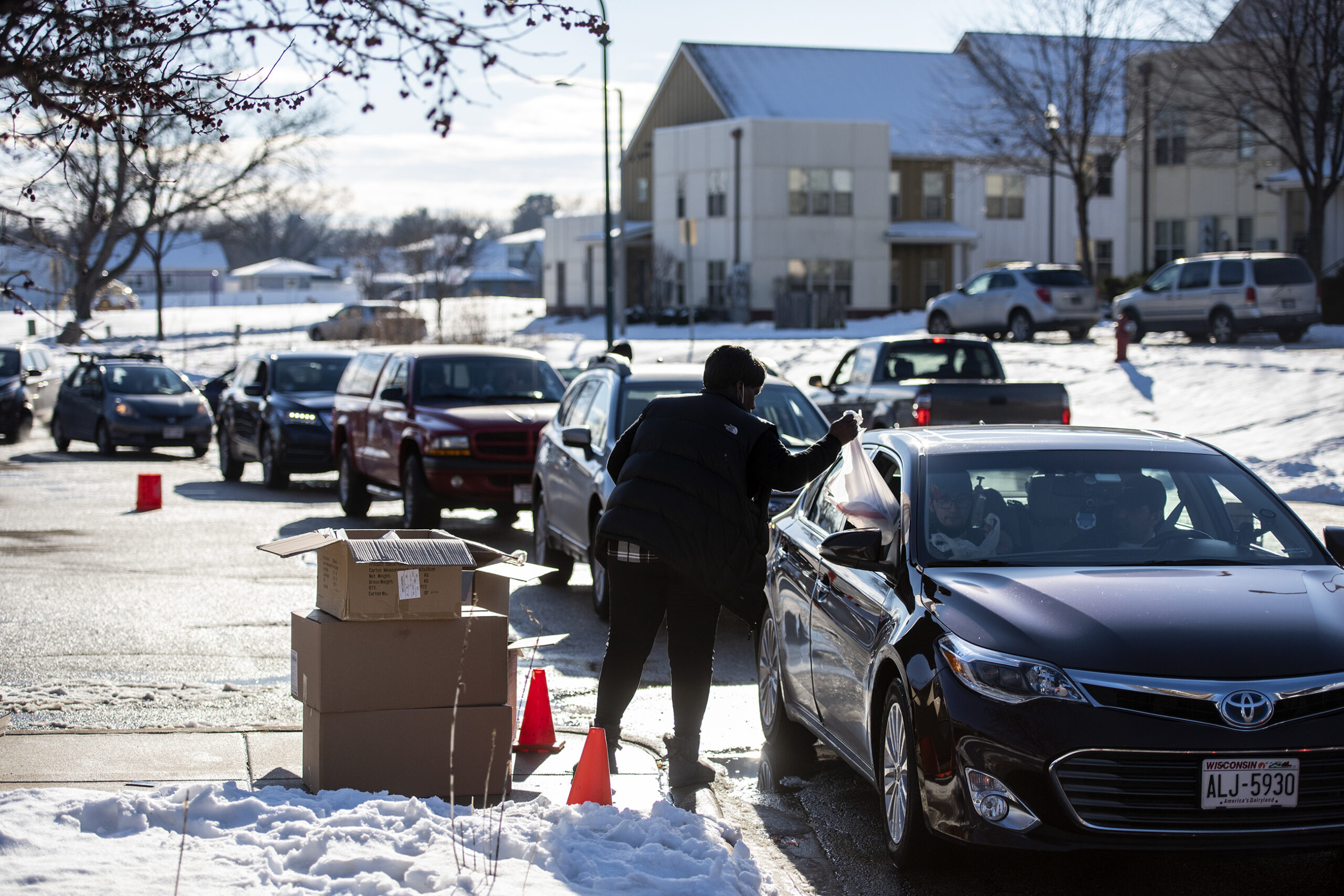 Drivers in cars wait in a line to get masks.