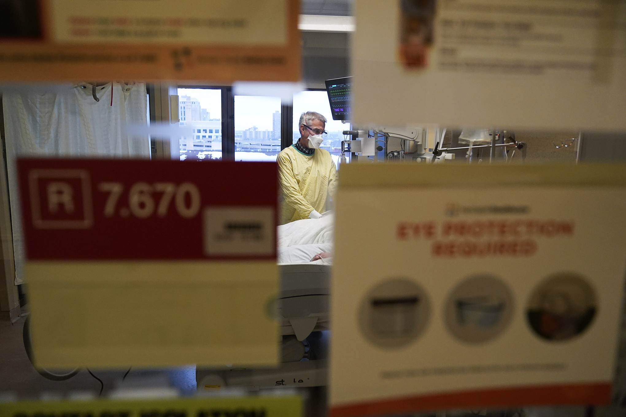 Steve Grove, a chaplain at Hennepin County Medical Center, prays in a COVID-19 patient's room