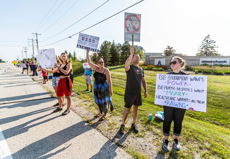 Protesters hold up signs in front of Ascension SE Wisconsin Hospital in Franklin