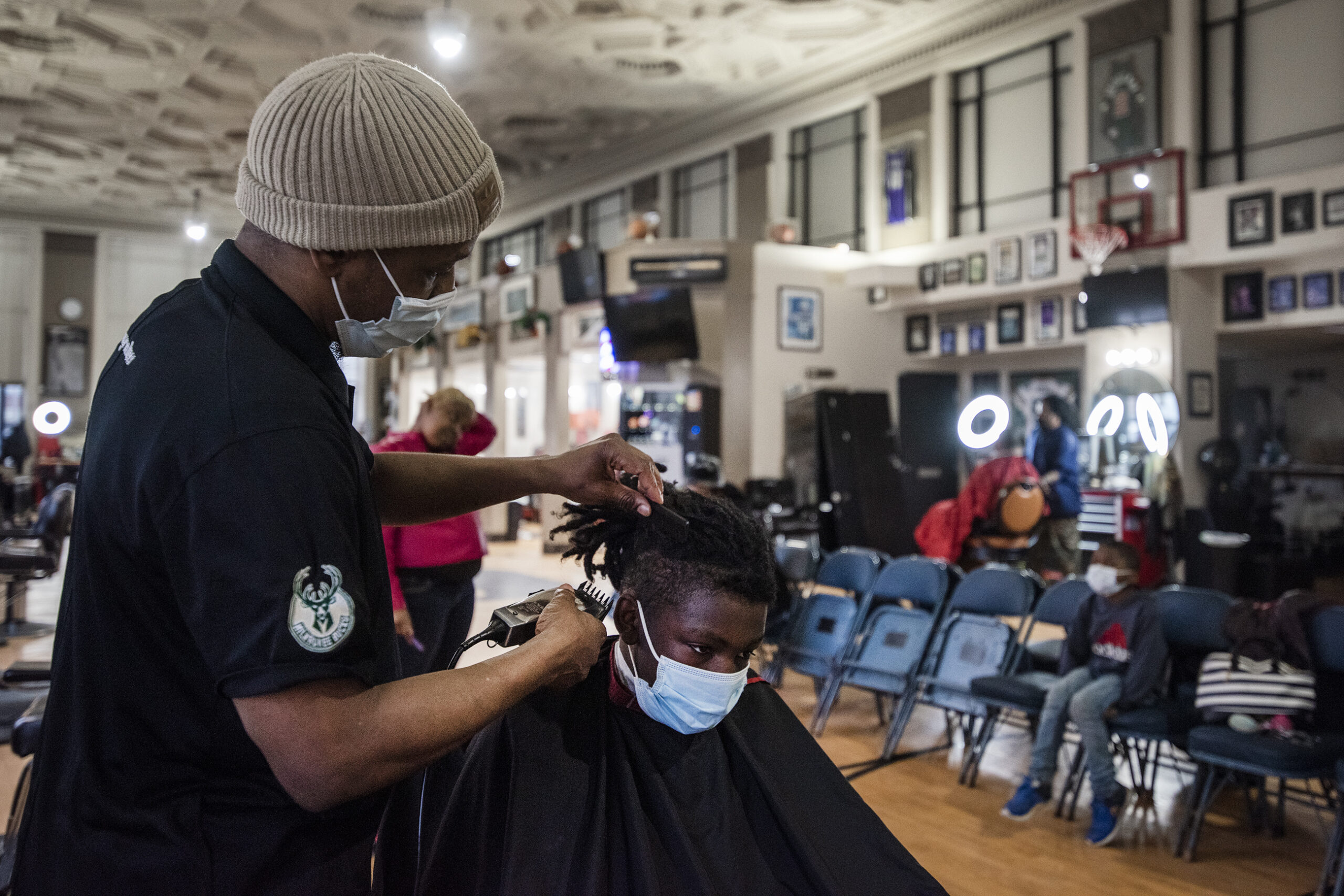 A man cuts a client's hair at a barber shop.