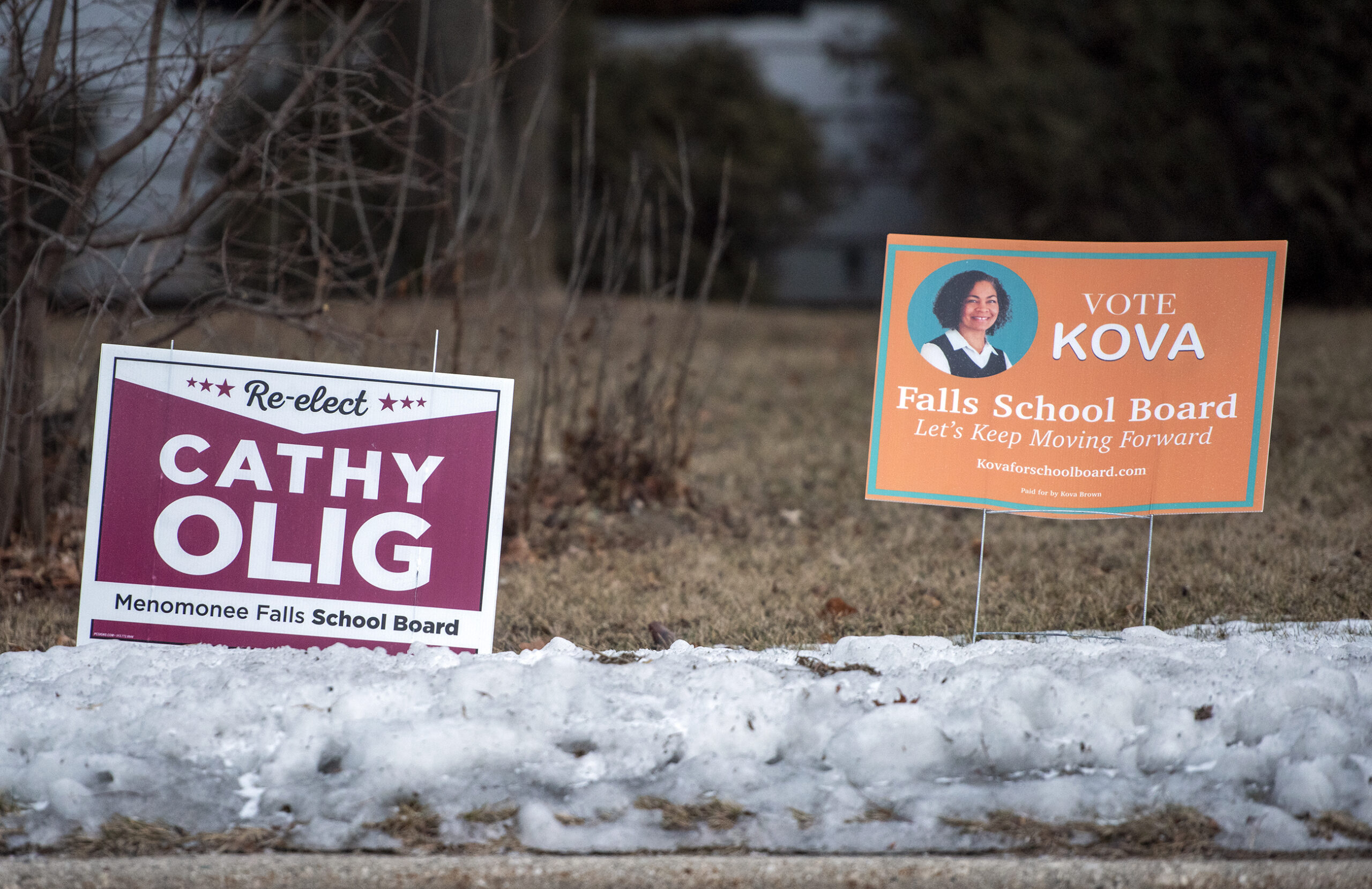 Two yard signs display names of school board candidates.